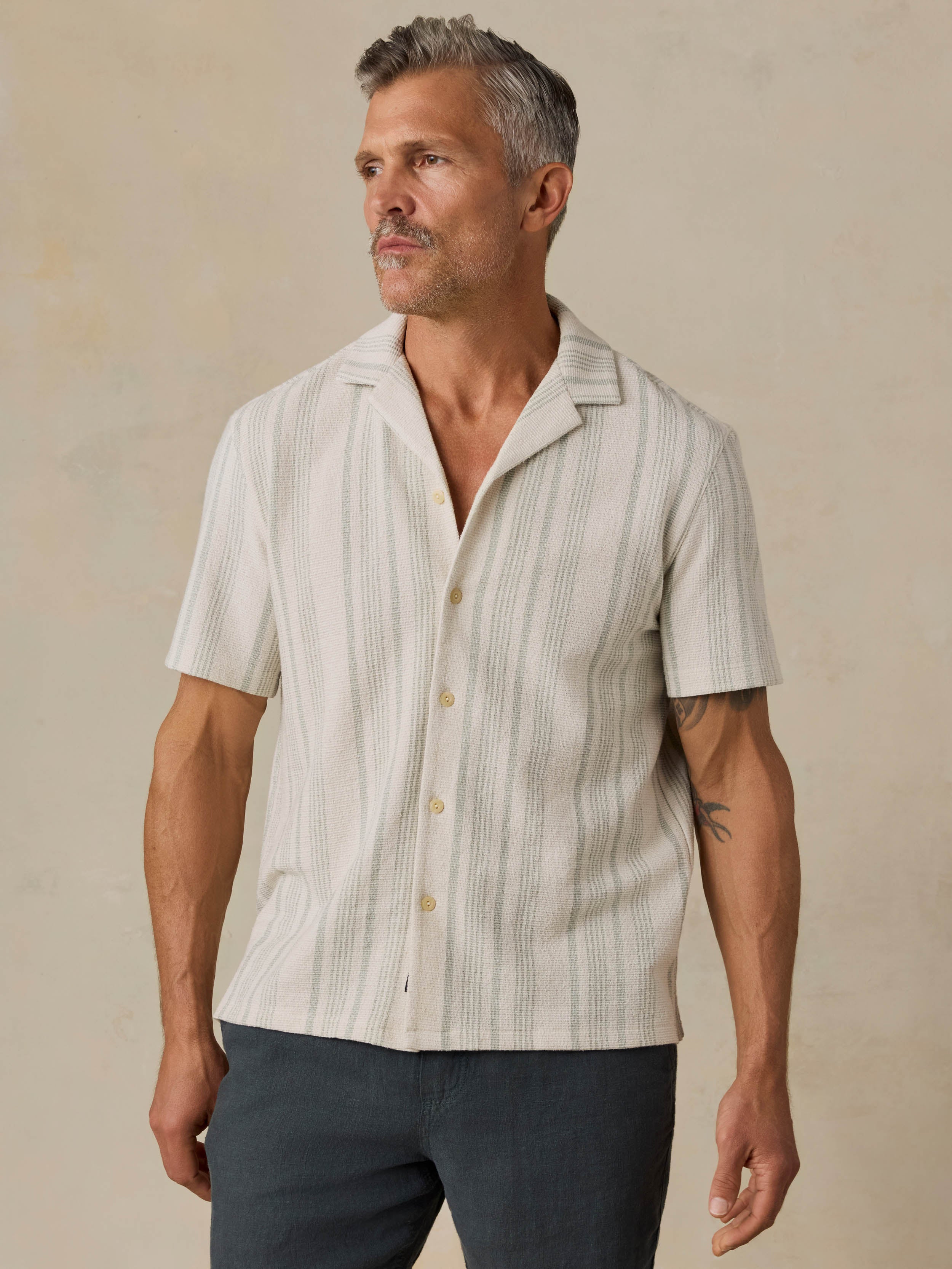 Man wearing a beige striped shirt against a beige background