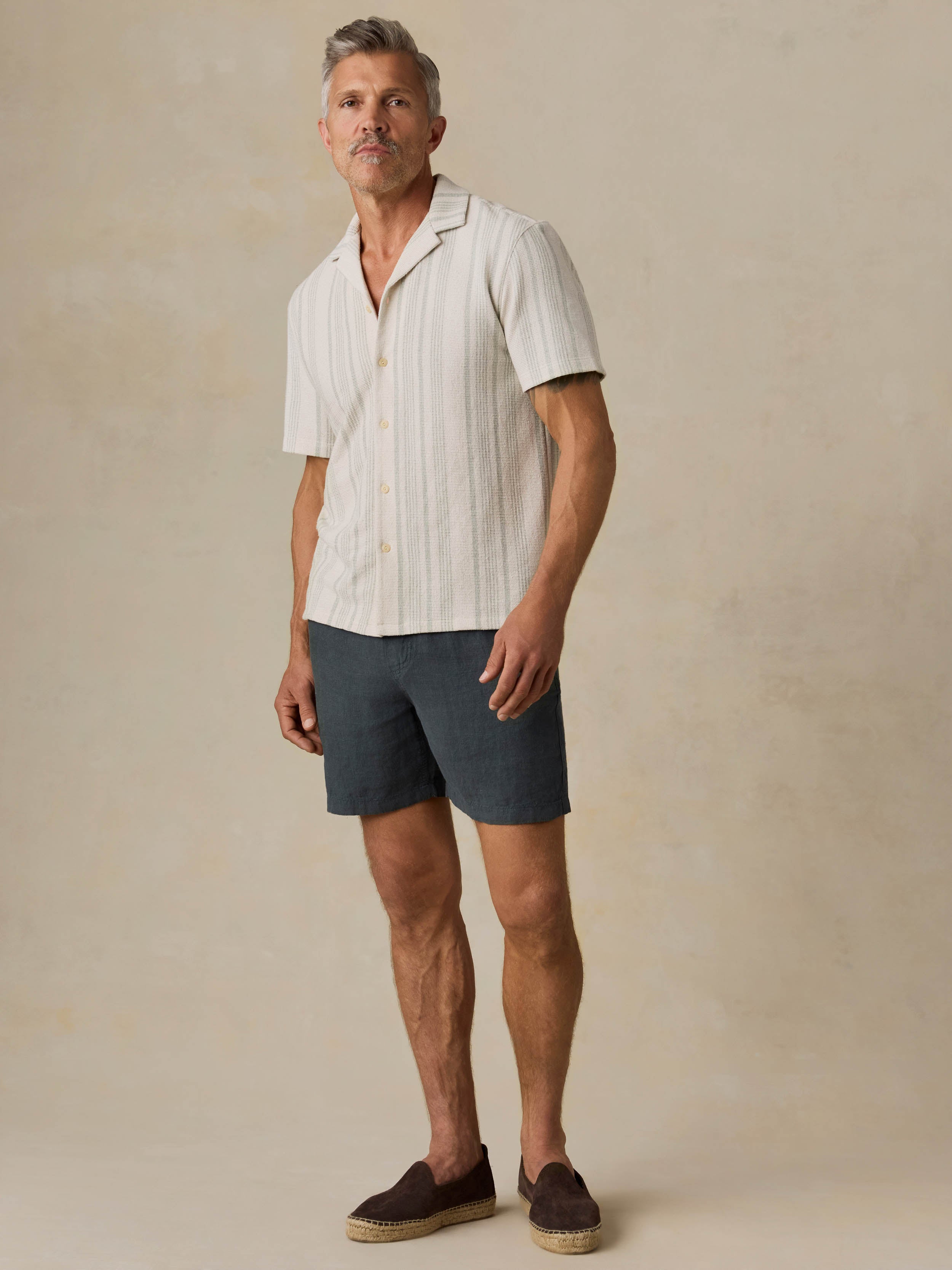 Man wearing a beige striped shirt against a beige background