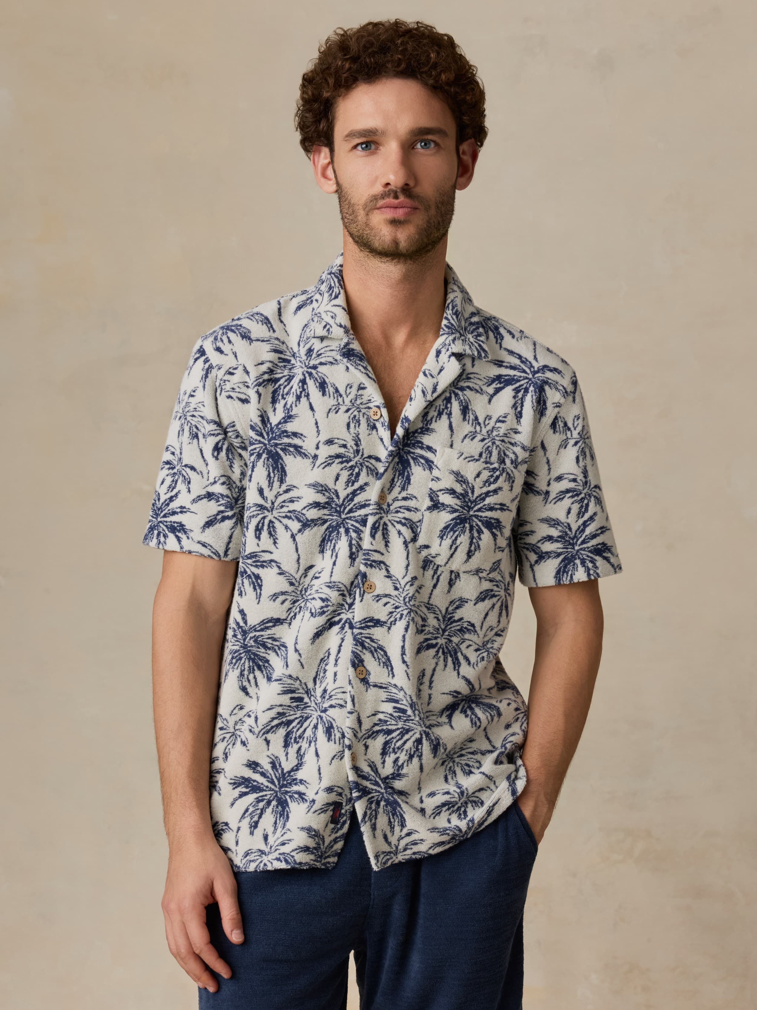 Man wearing a tropical patterned shirt with a neutral background