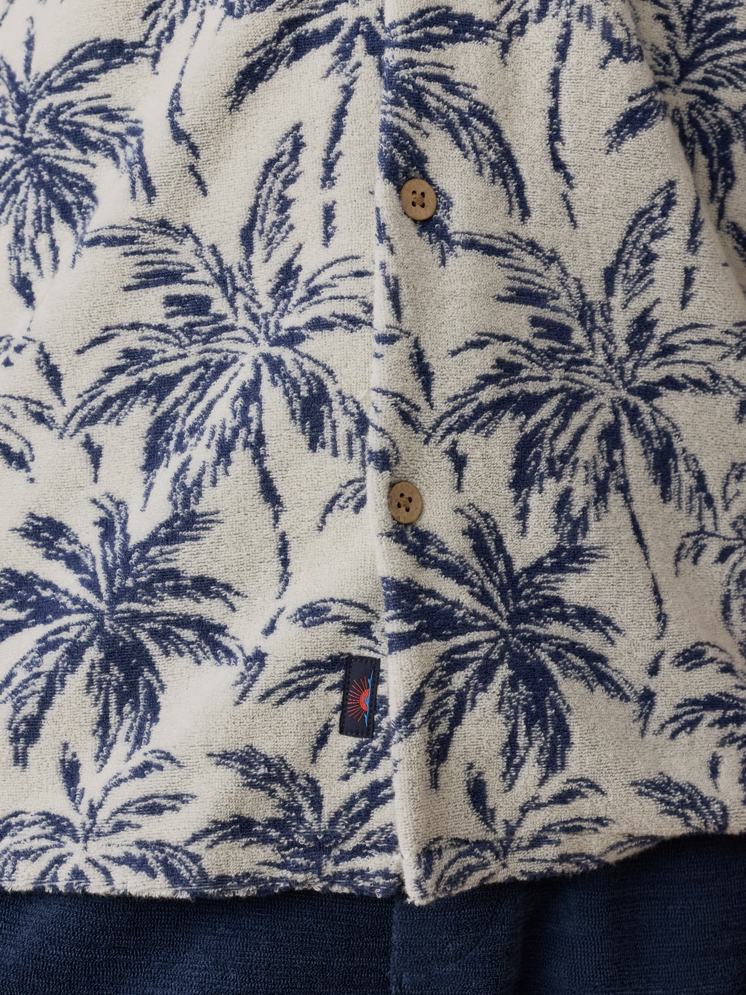 Close-up of a shirt with navy palm tree pattern on a beige background