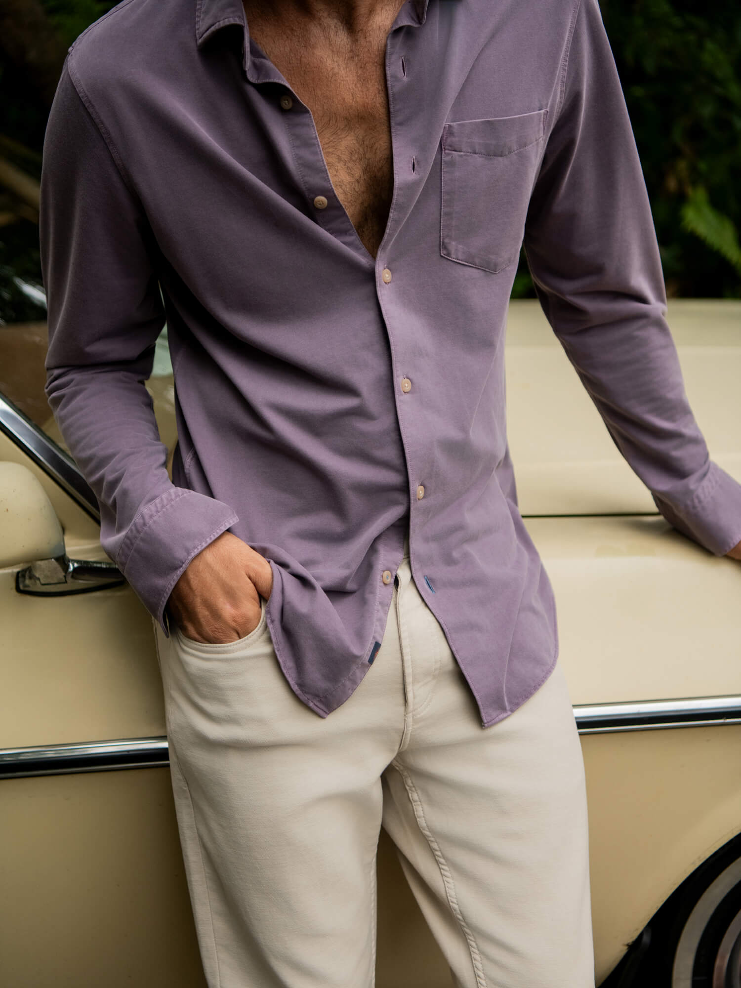 Man wearing a purple shirt and beige pants standing next to a vintage car