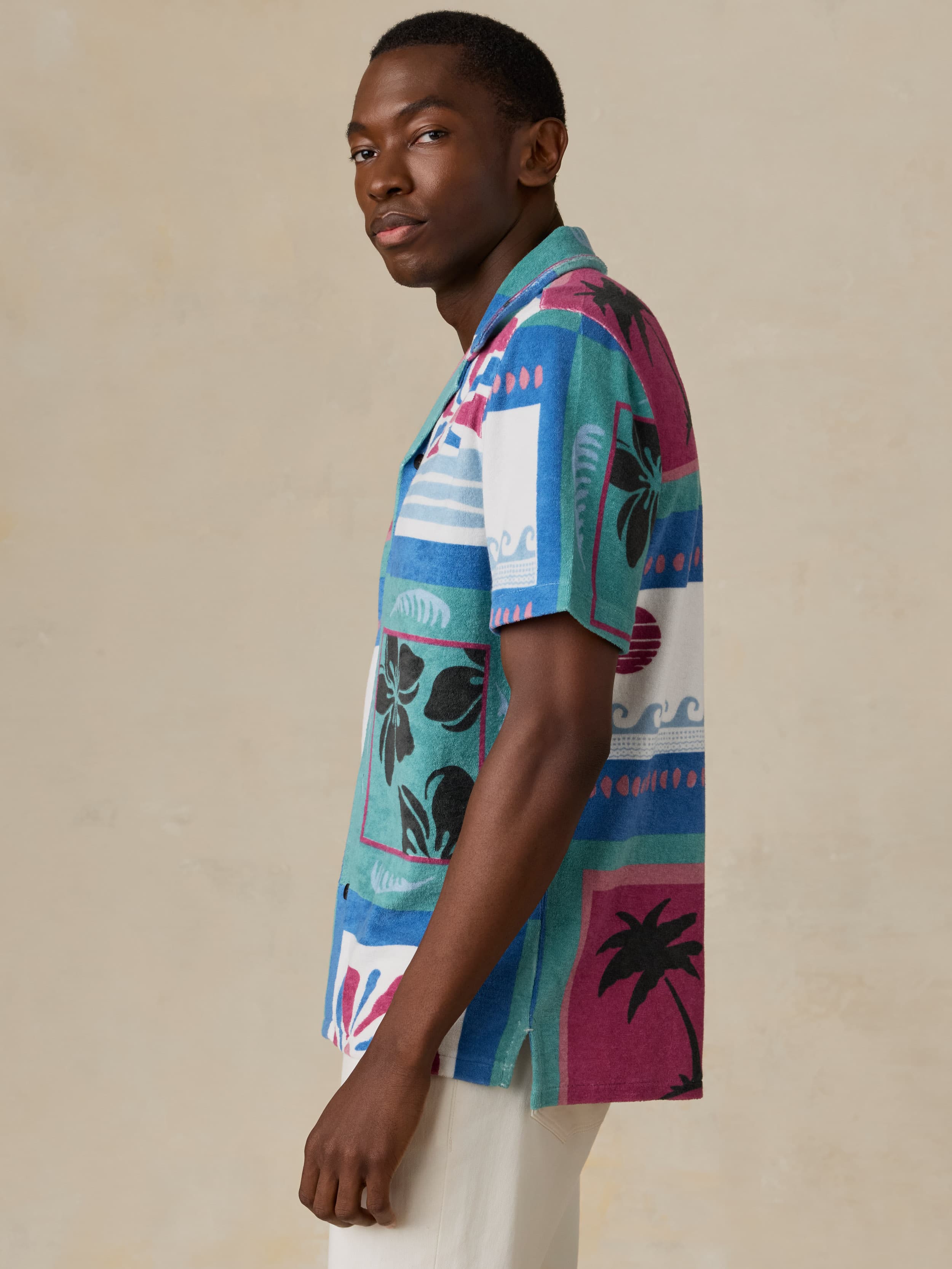 Man wearing a colorful patterned shirt against a beige background