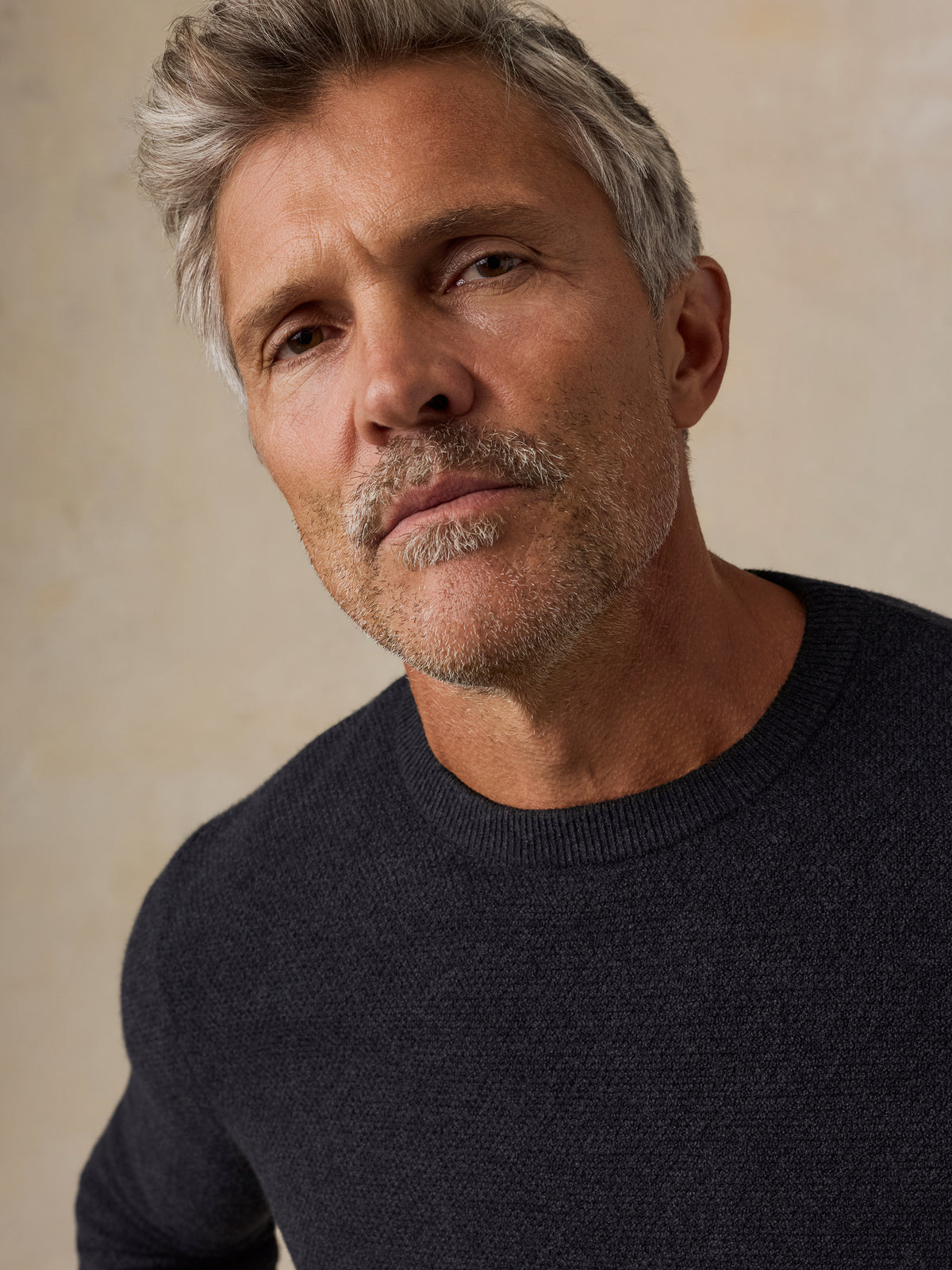 A close-up of a man wearing a dark charcoal knit crewneck sweater , image 3 of 7