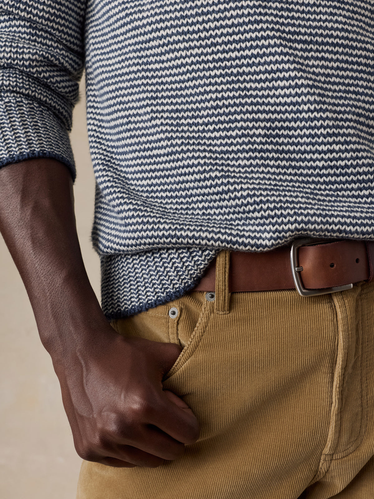 Close up of a man wearing a blue striped sweater and tan corduroy pants, image 3 of 5