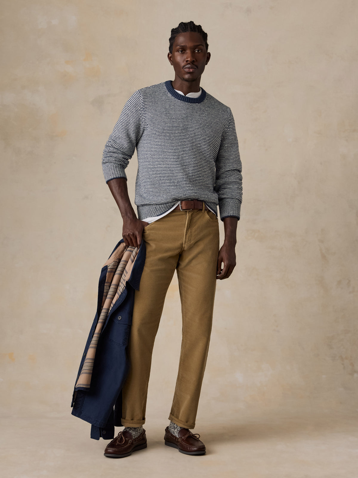 A man wearing a blue striped sweater and tan corduroy pants, image 5 of 5