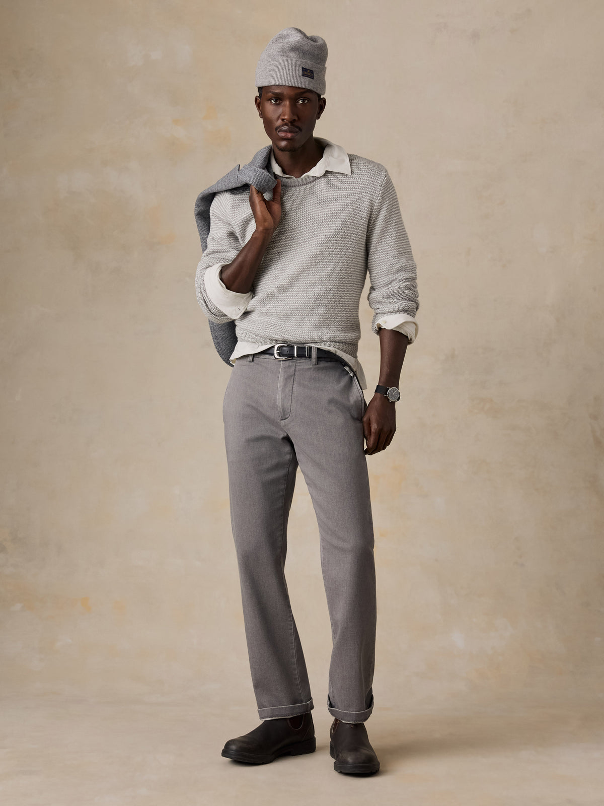 Man wearing a light grey sweater over a white shirt and grey pants, image 4 of 5