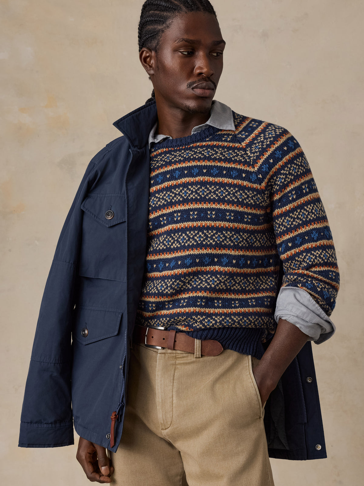 Man wearing a blue jacket over a nordic printed sweater and beige pants , image 5 of 6