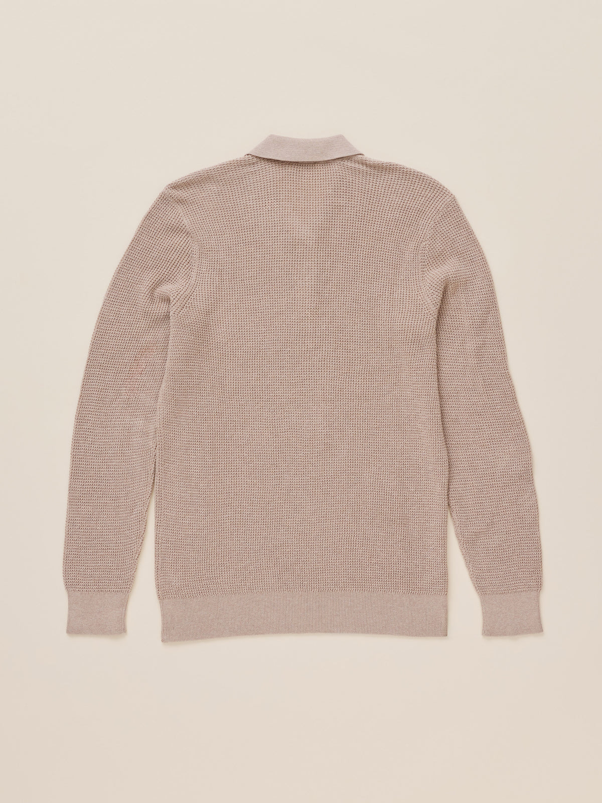 A light beige knit polo shirt shown from the back, laid flat against a matching light beige background., image 8 of 8