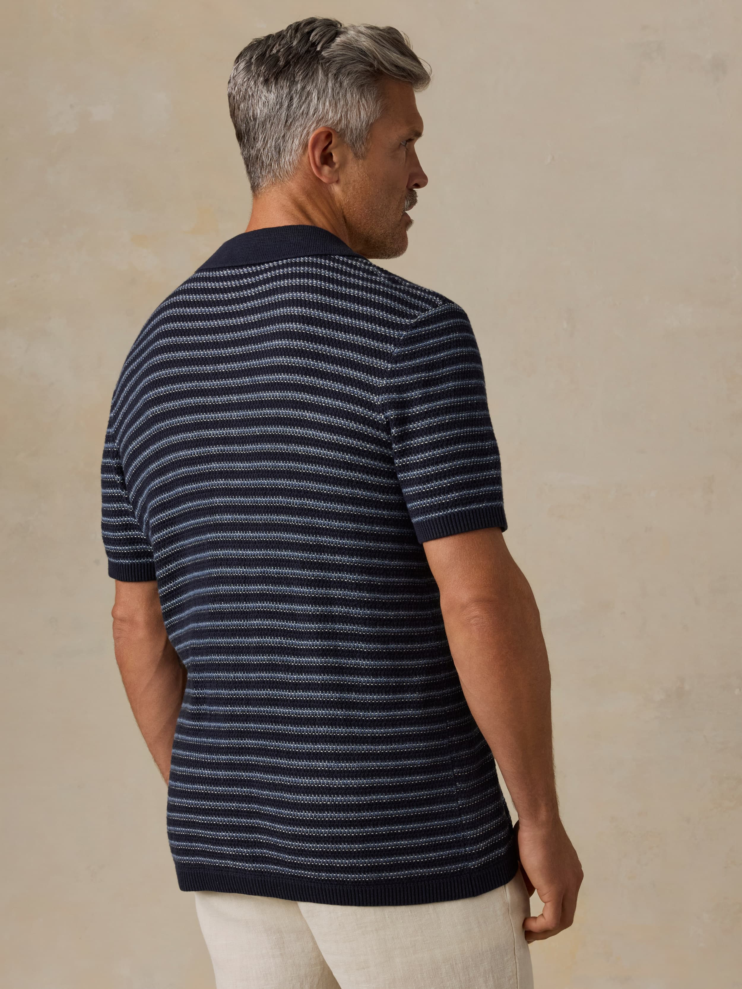 Man wearing a striped polo shirt against a beige background