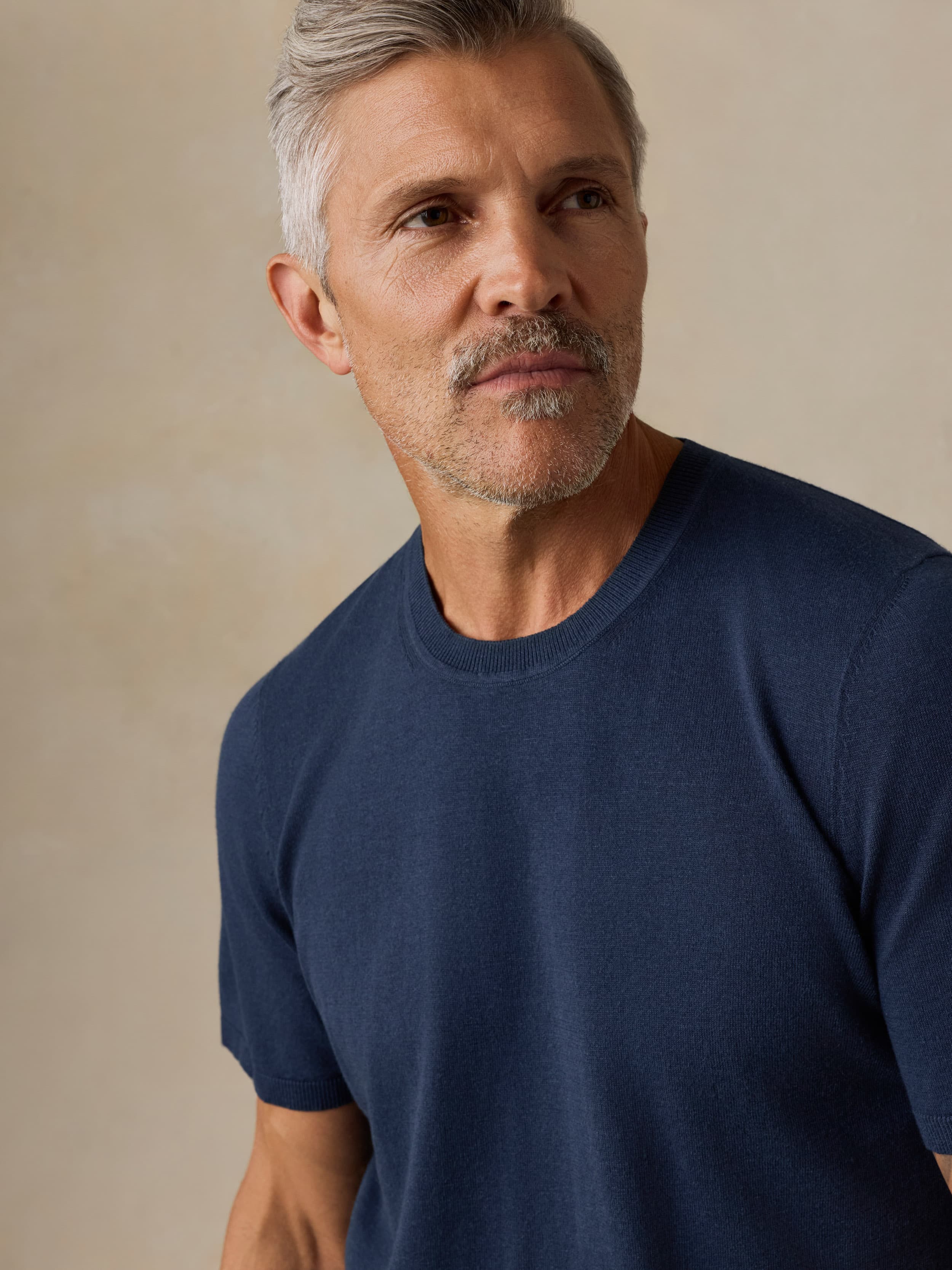 Man wearing a navy blue t-shirt against a beige background