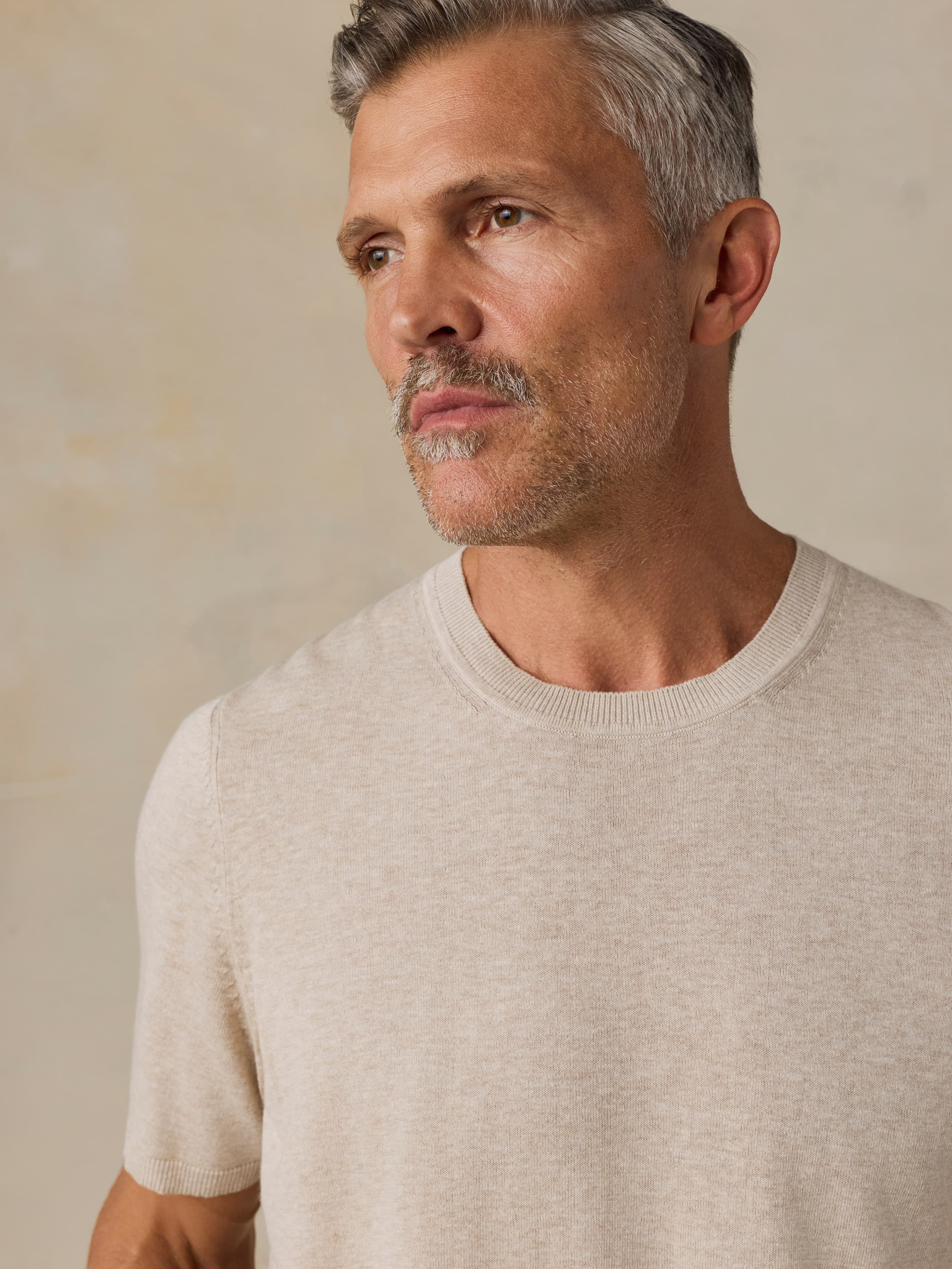 Man wearing a beige t-shirt against a beige background