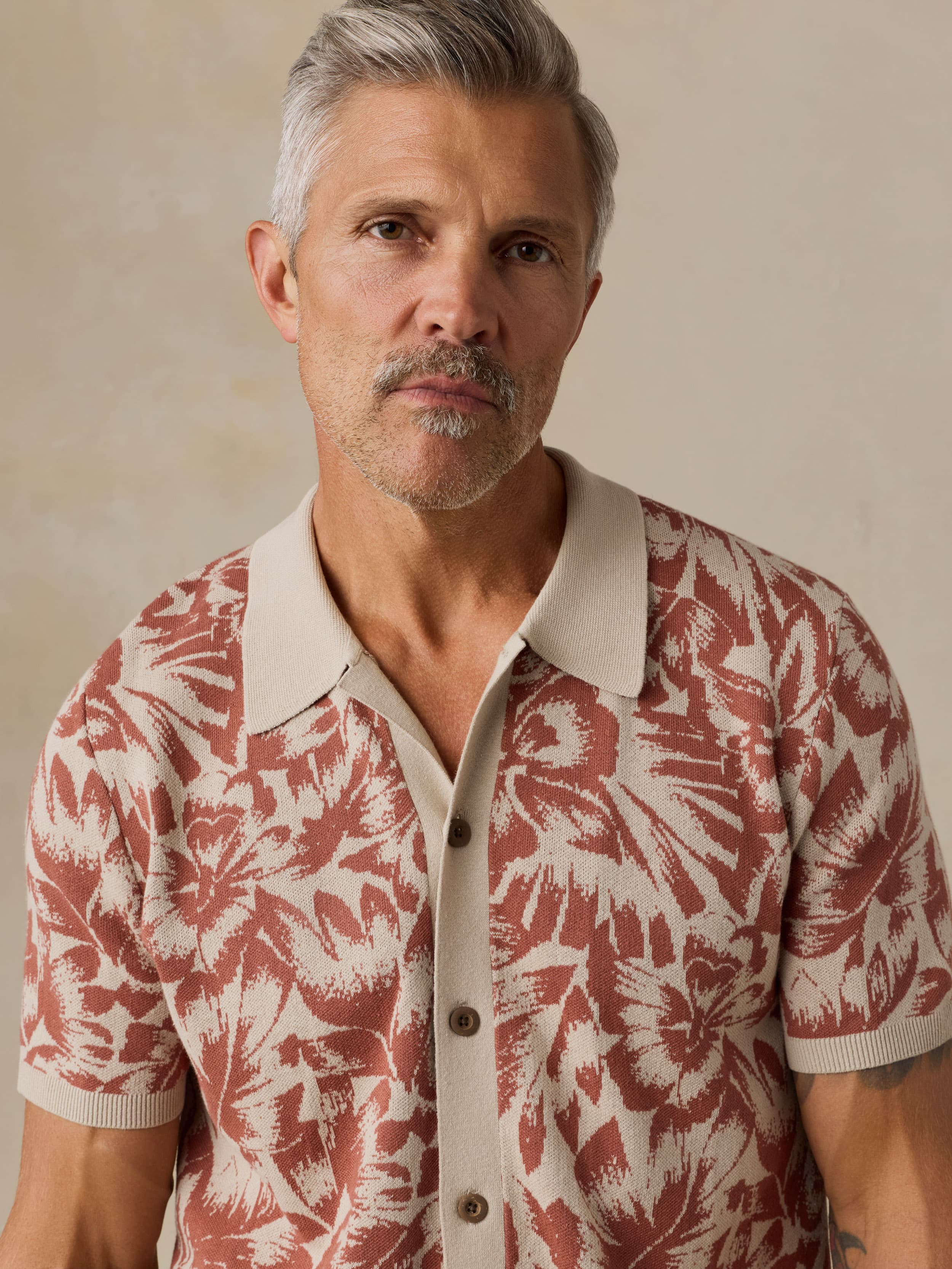 Man wearing a red and white floral patterned shirt against a beige background