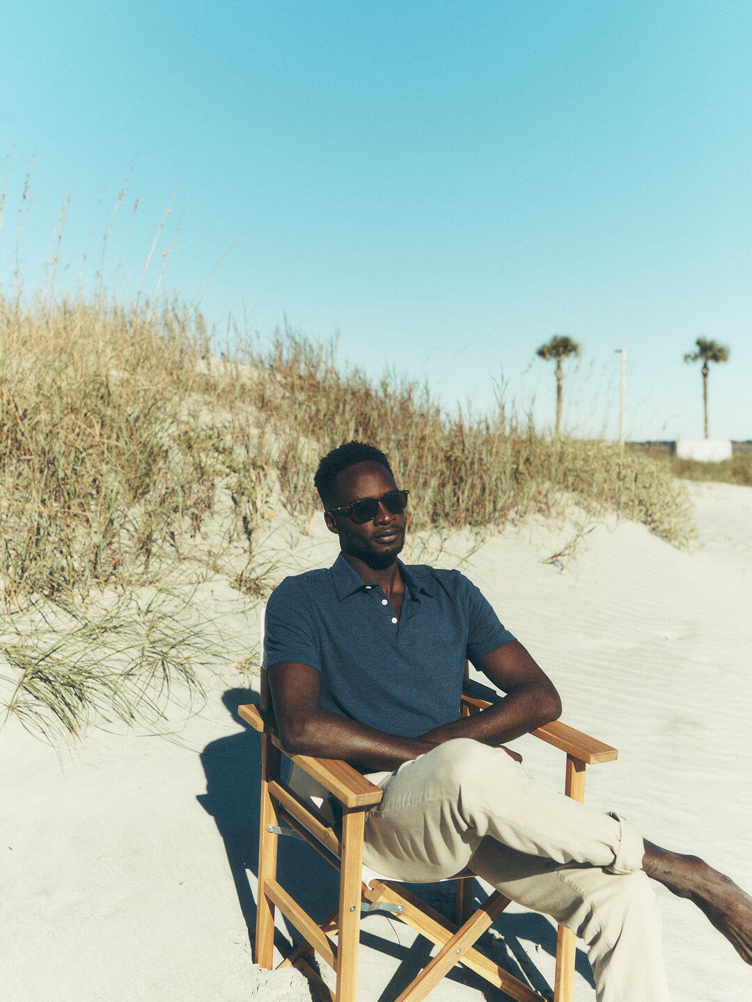 A model sitting in a chair on the beach wearing a polo t shirt and stretch terry pants