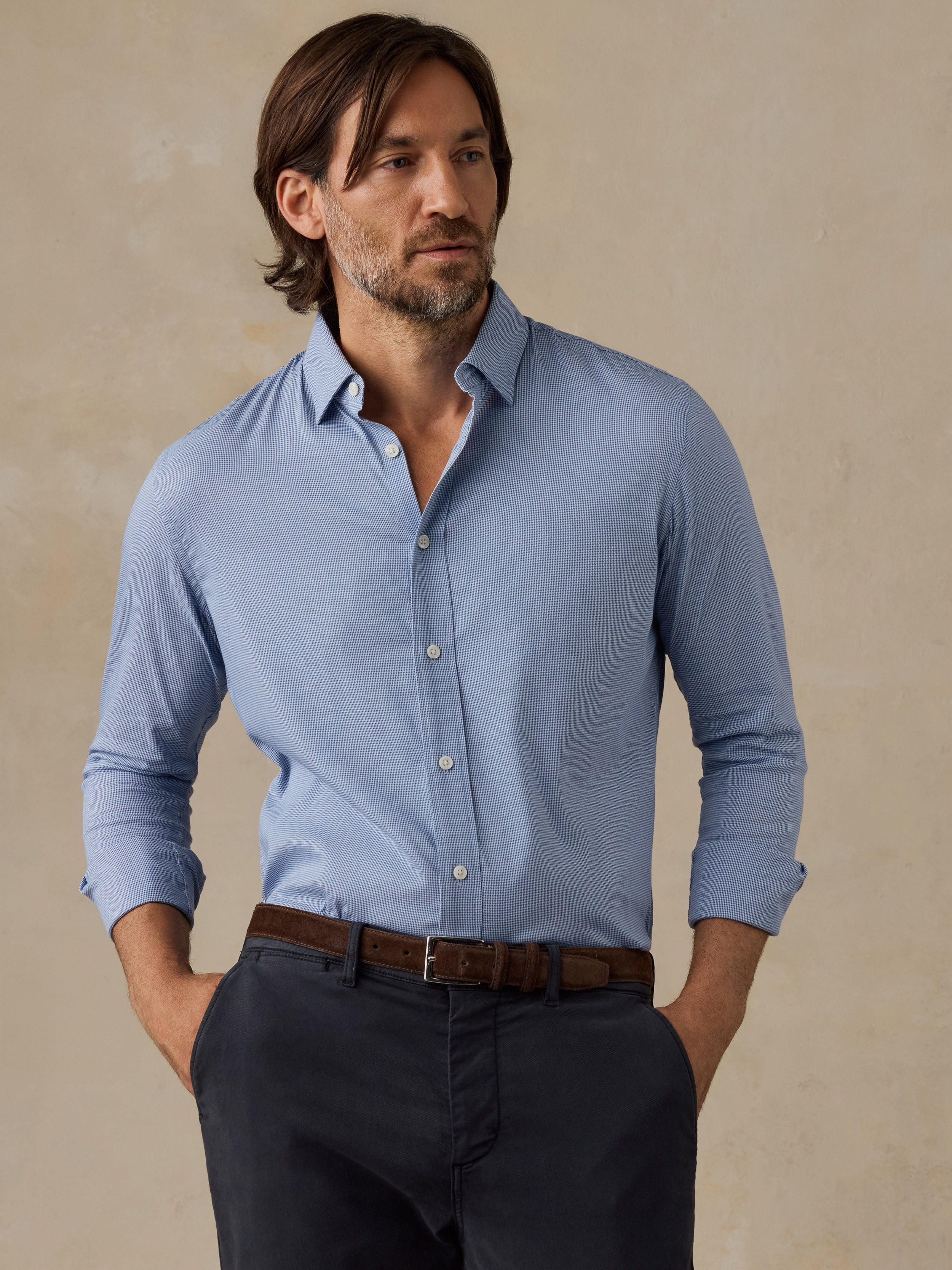 Man wearing a light blue button-up shirt against a beige background