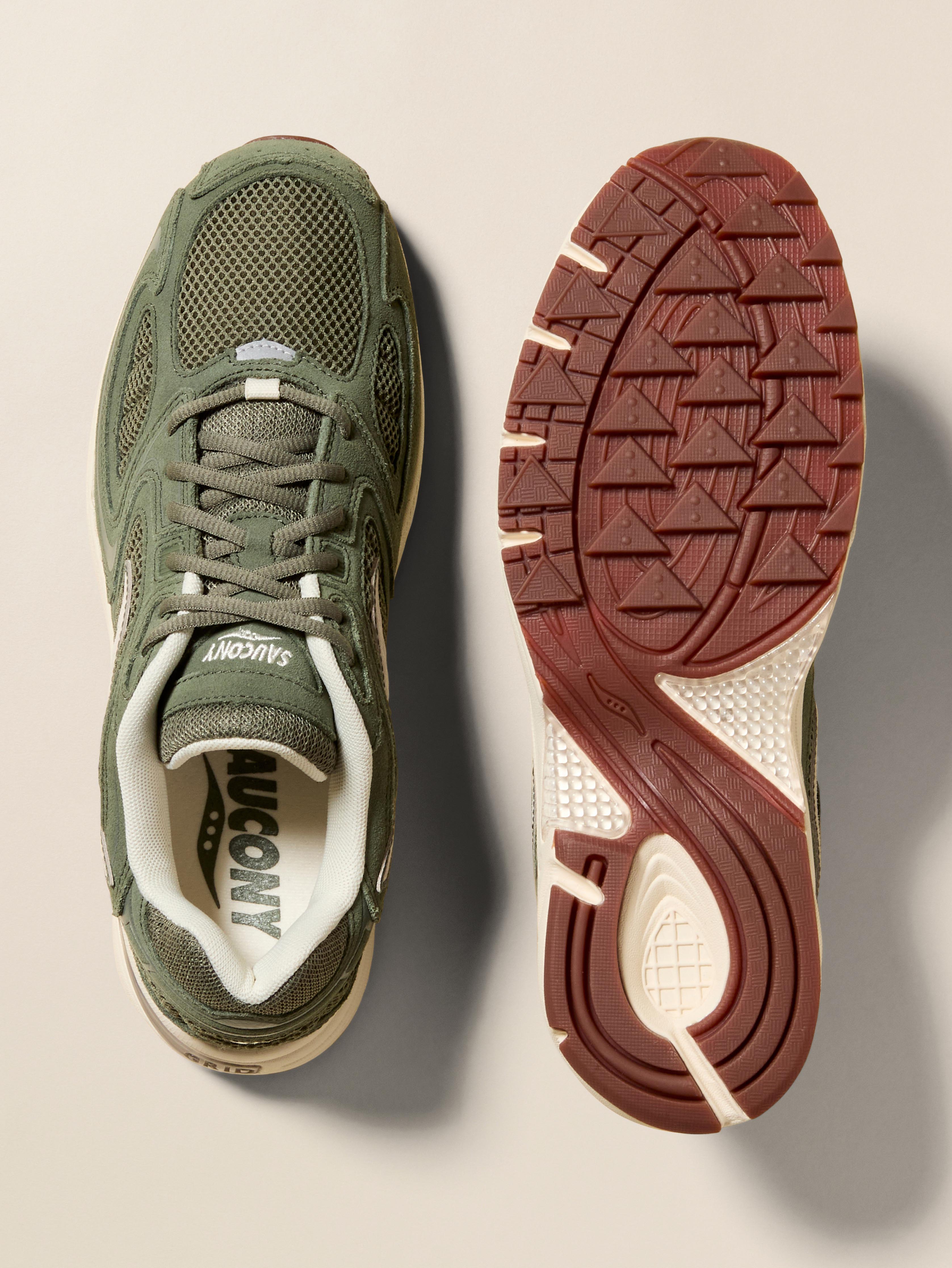 Pair of green Saucony running shoes on a beige background