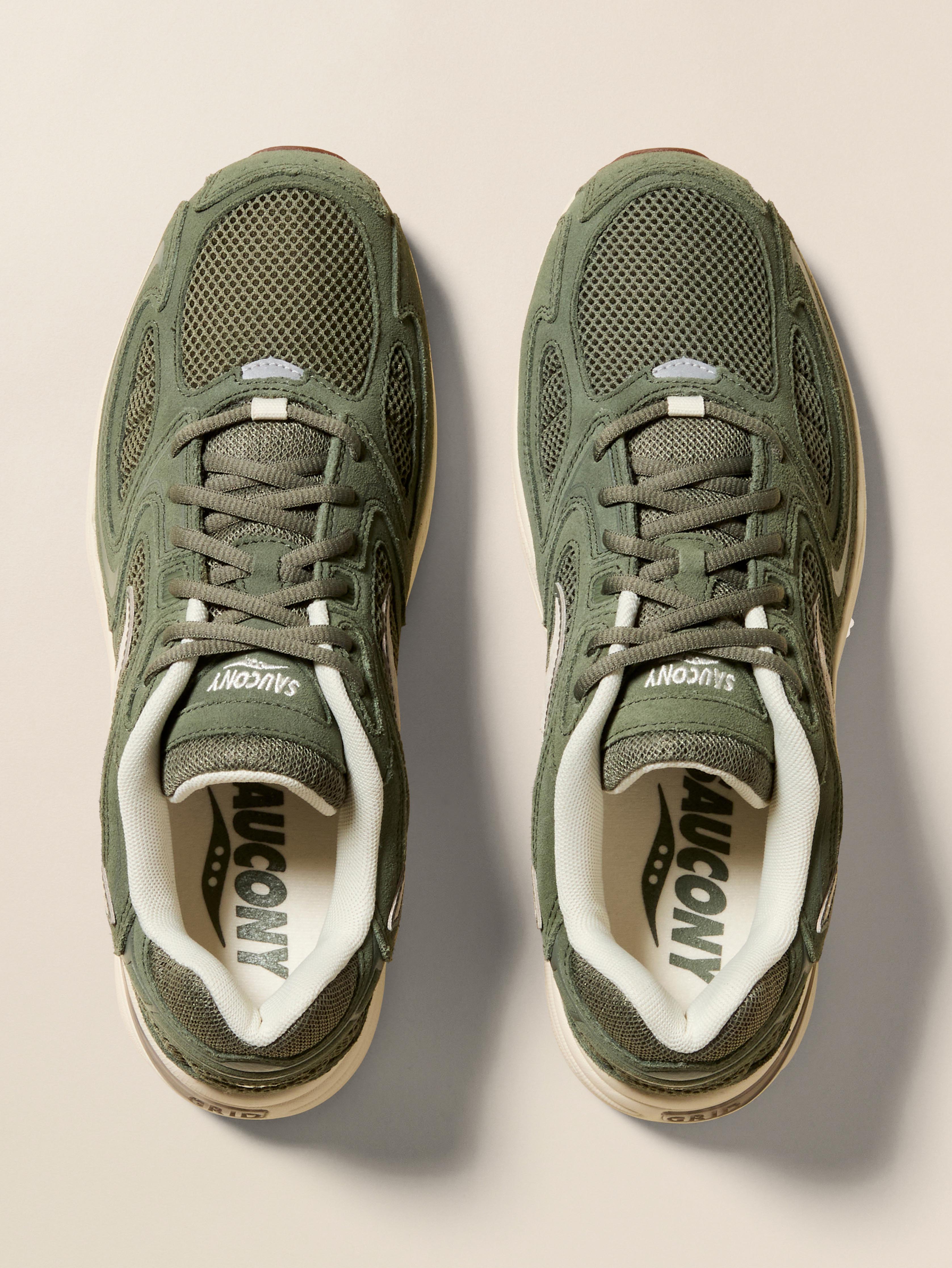 Pair of green Saucony running shoes on a beige background