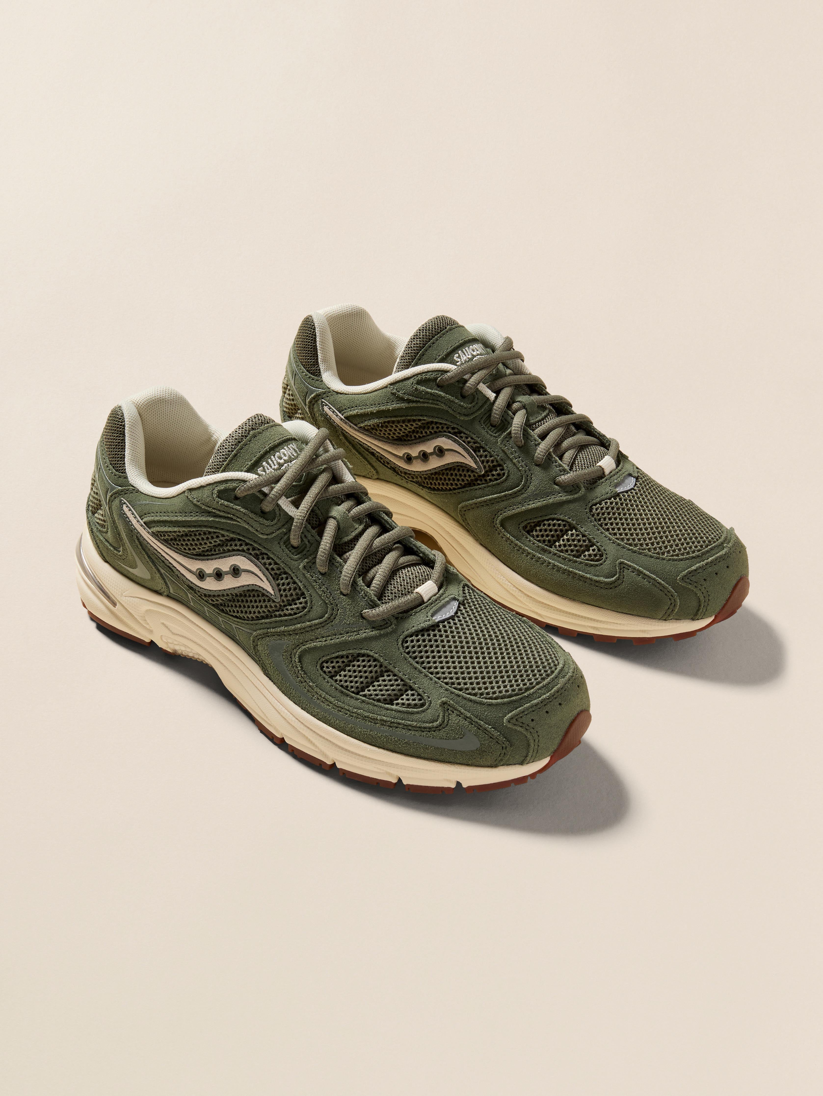 Pair of green Saucony running shoes on a beige background