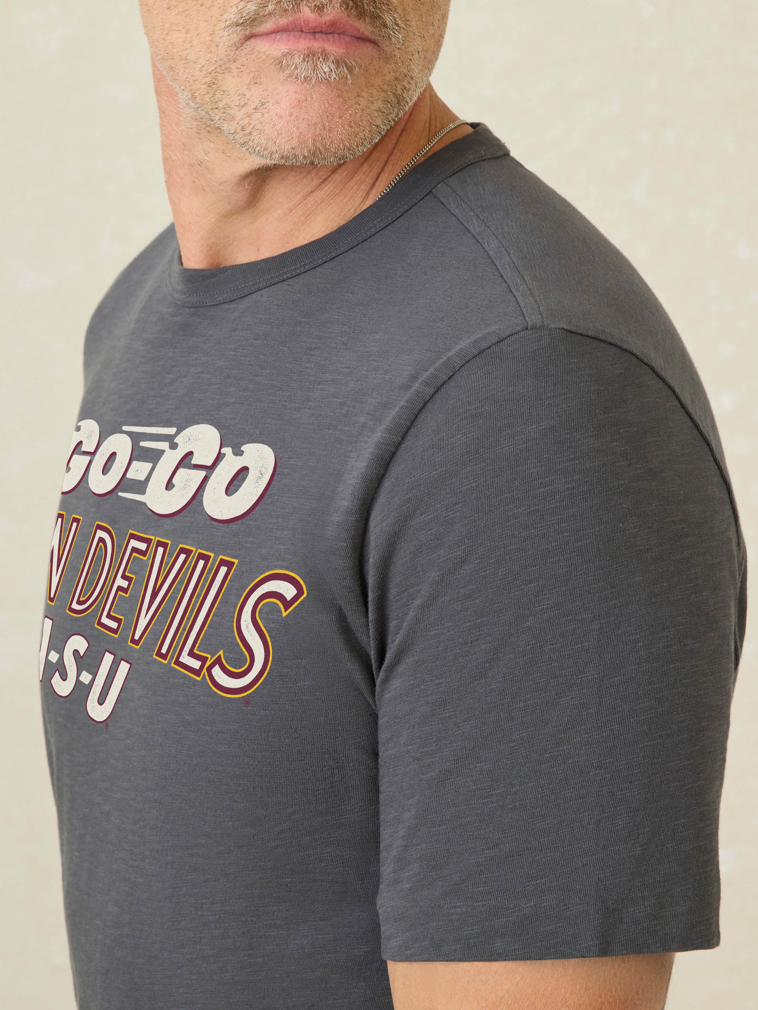 Man wearing a grey short sleeve t-shirt with Arizona State University graphic on the center front against a beige background