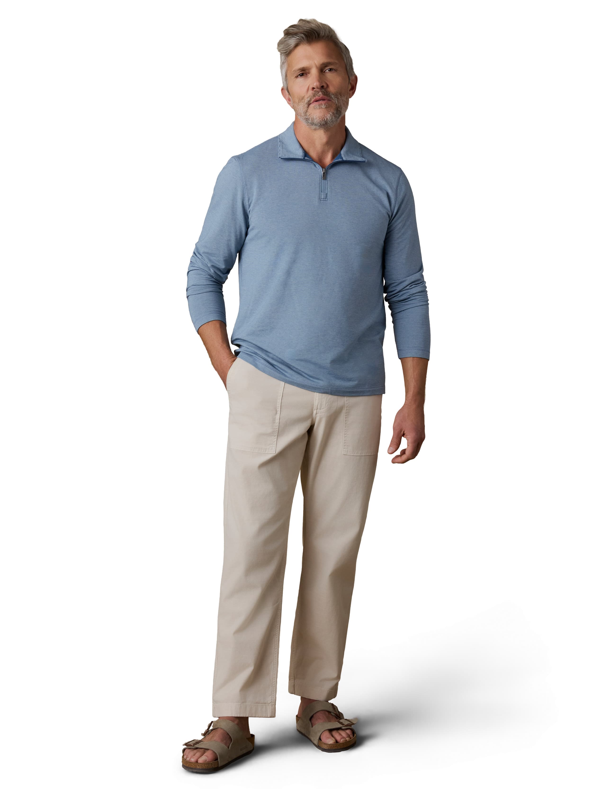 A man wearing a blue polo, beige pants, and birkenstocks