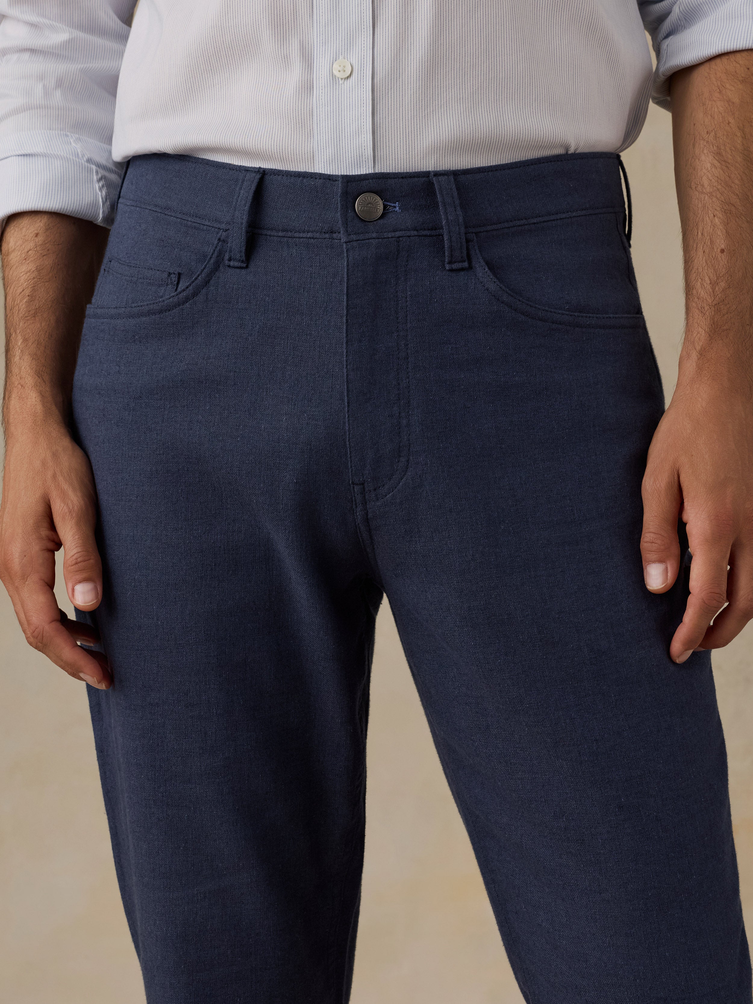 Man wearing a blue checkered shirt and navy pants on a beige background