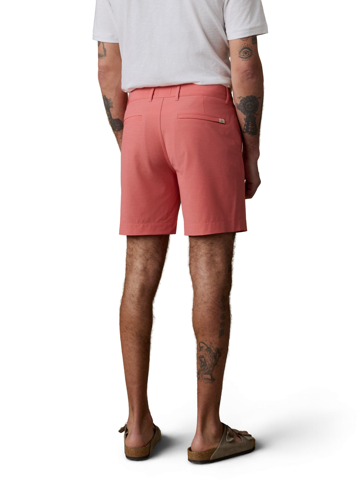 A man wearing a white henley tee, coral shorts, and birkenstocks, image 3 of 3
