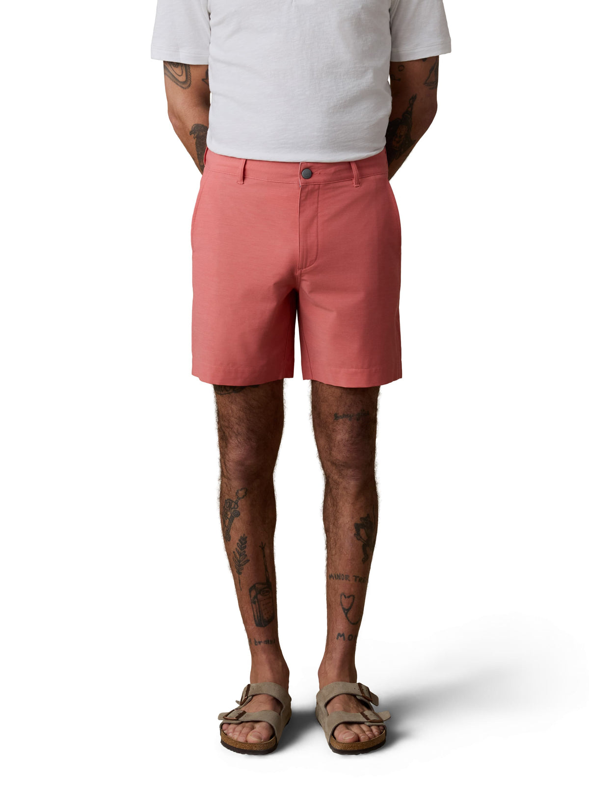 A man wearing a white henley tee, coral shorts, and birkenstocks, image 2 of 3