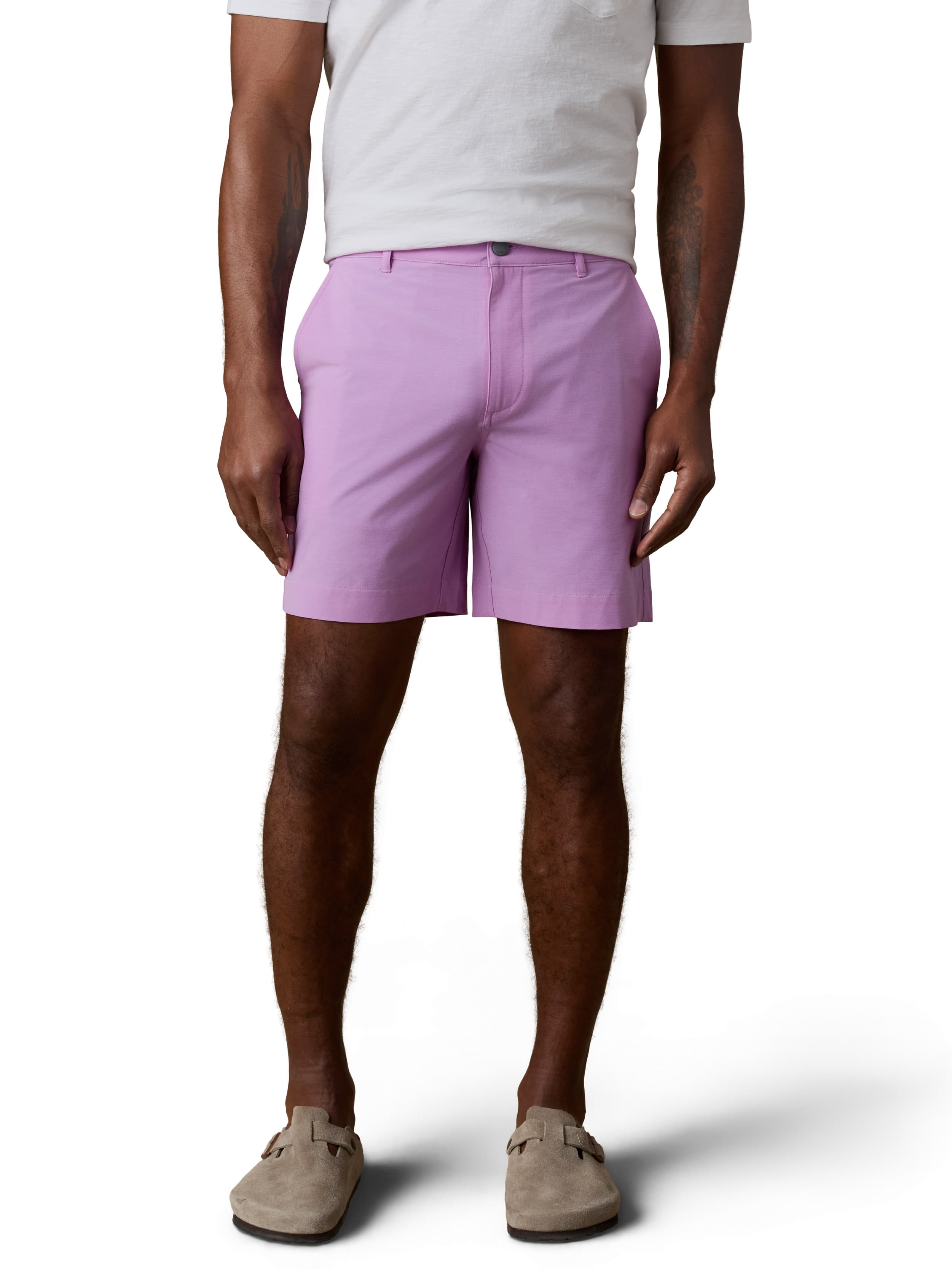 A man wearing a white tee, purple shorts, and birkenstocks