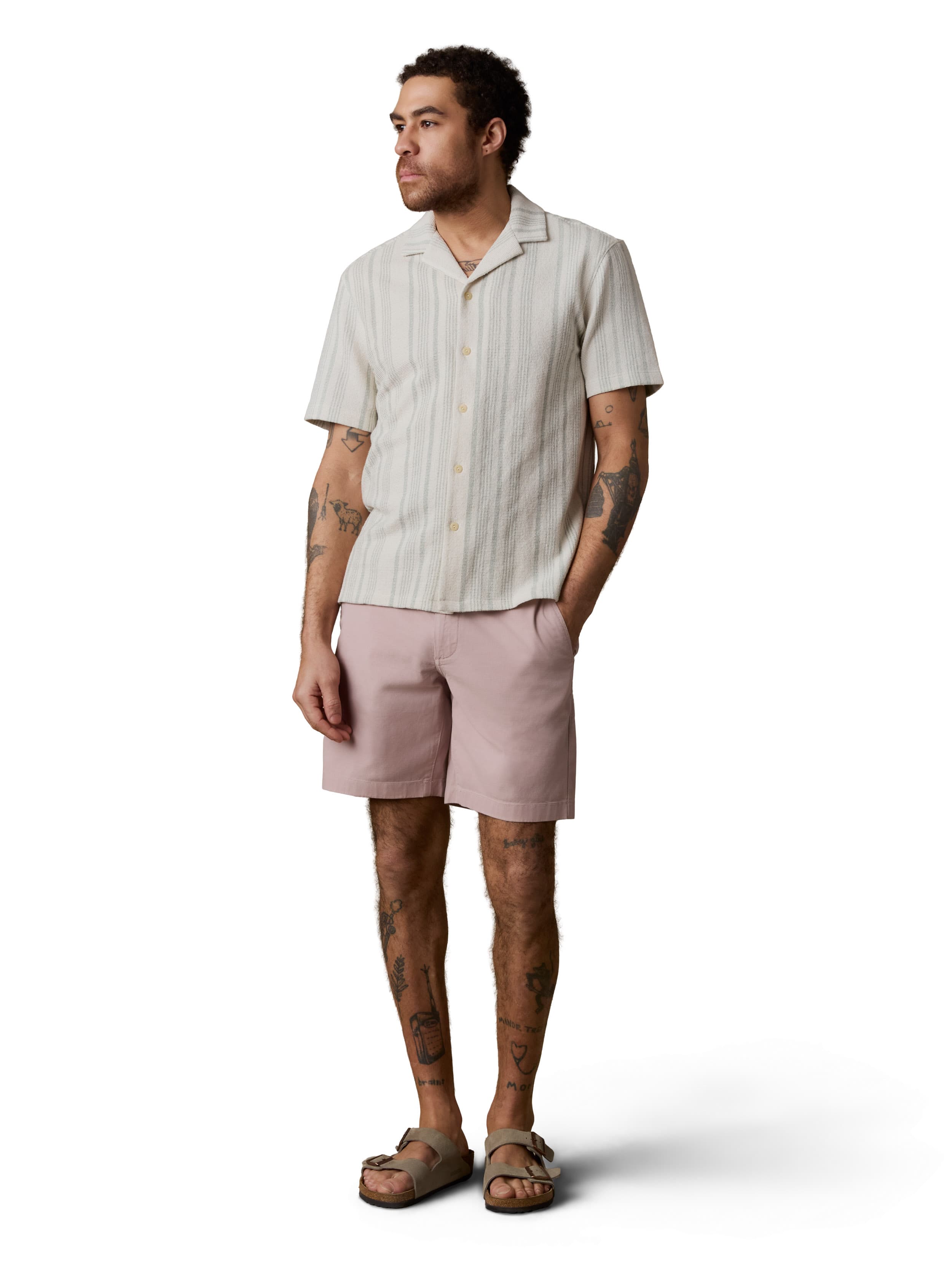 A man wearing a white striped button up shirt, pink pants, and birkenstocks