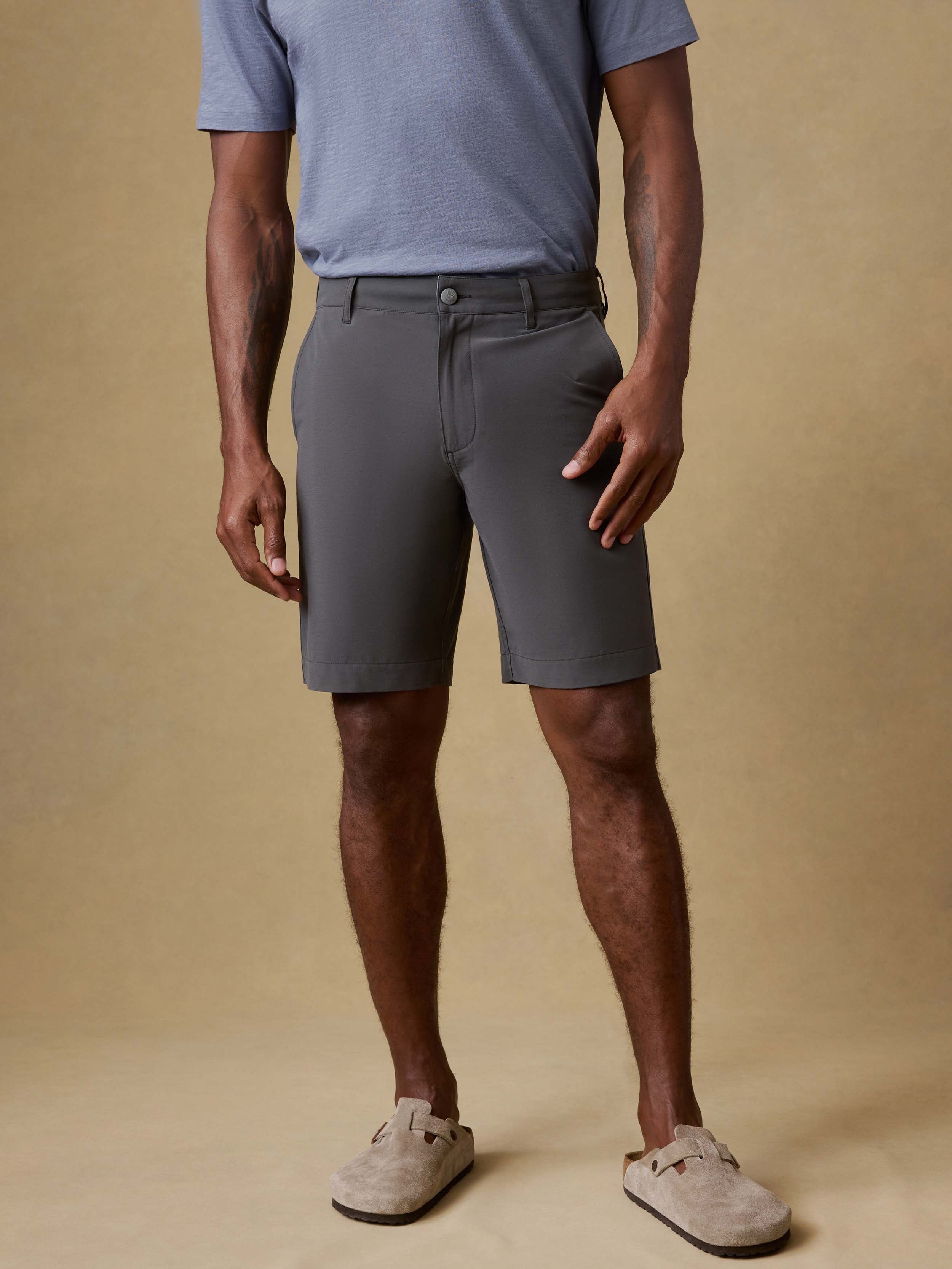 Man wearing gray shorts and a blue shirt on a beige background
