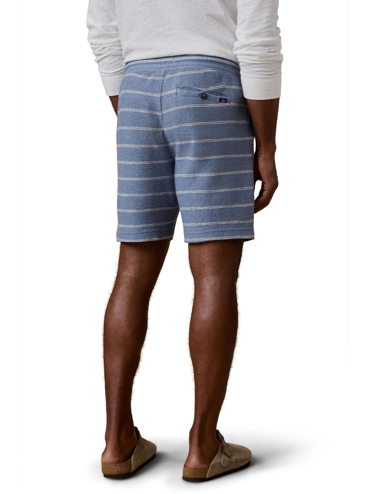 A man viewed from behind wearing blue and white striped shorts and white shirt, image 3 of 3
