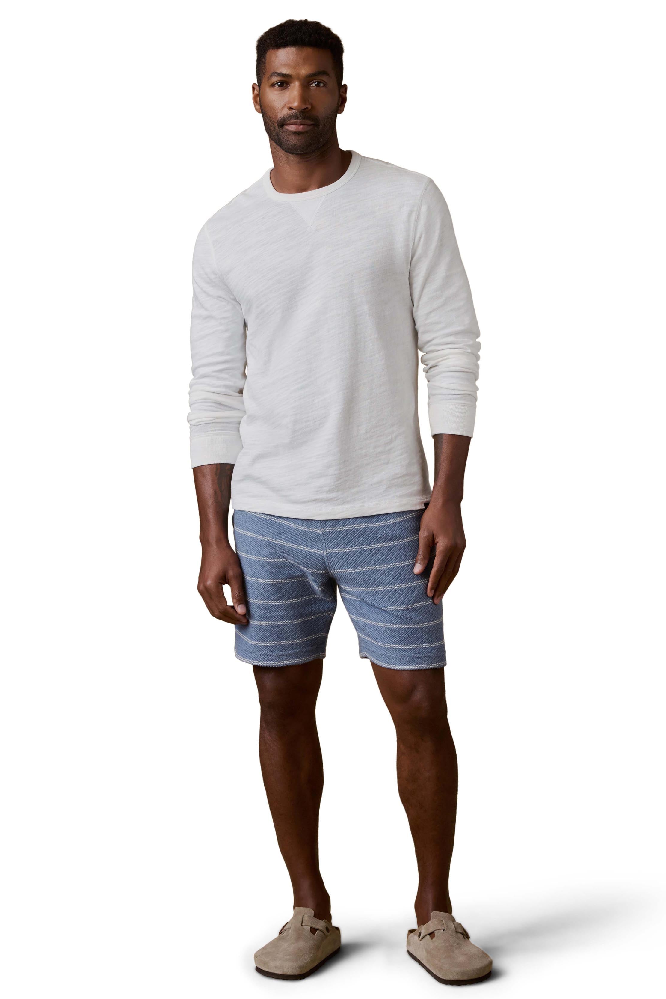 A man wearing blue and white striped shorts and white shirt