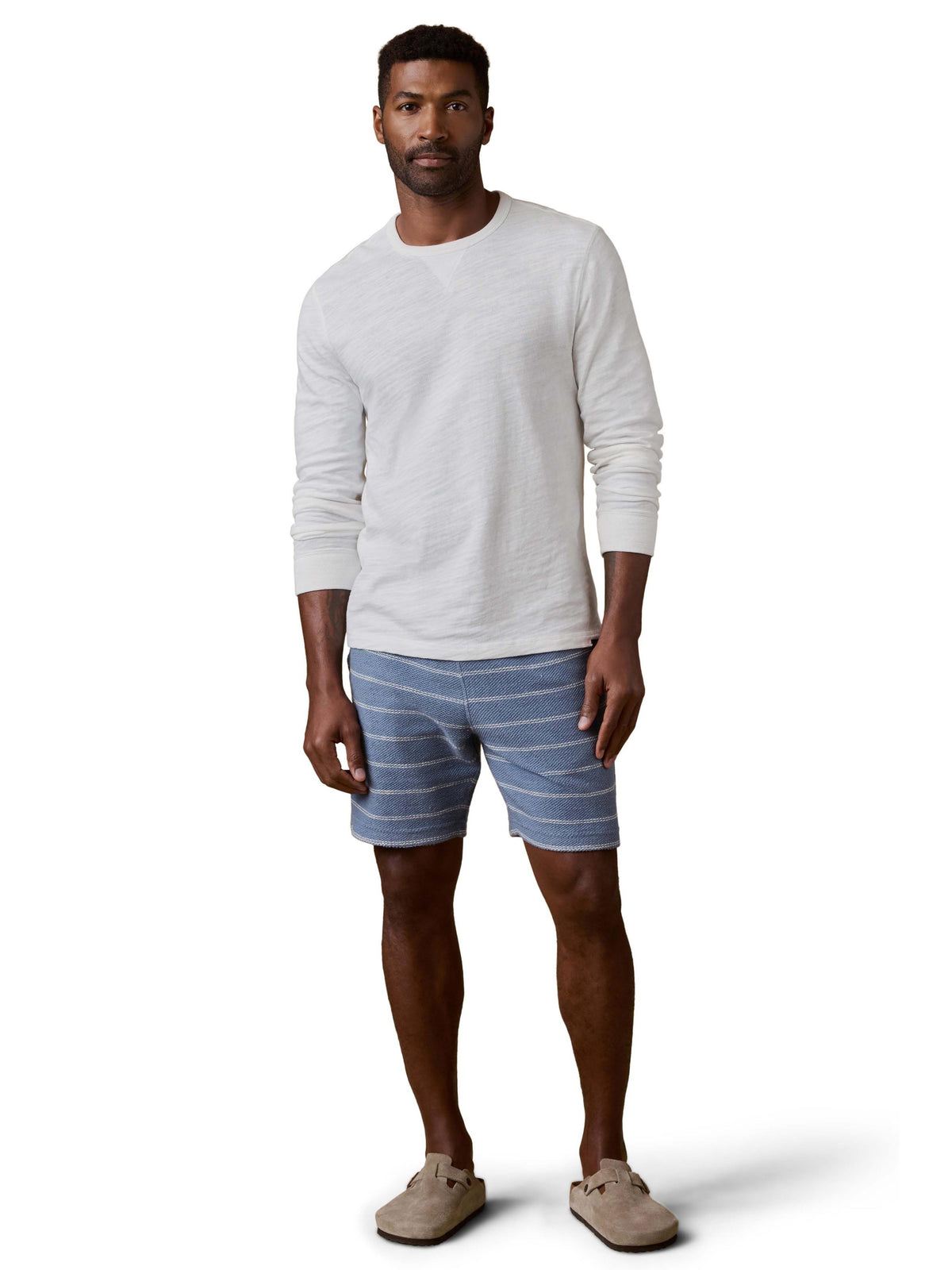 A man wearing blue and white striped shorts and white shirt, image 1 of 3
