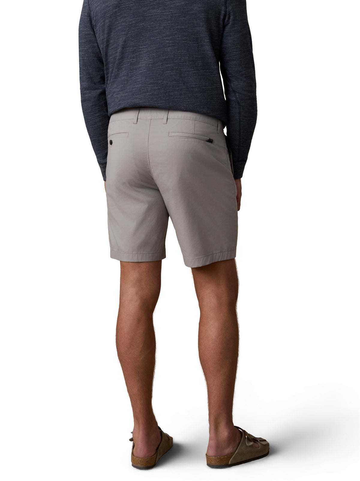 A man viewed from behind wearing a blue hoodie, grey shorts, and birkenstocks, image 3 of 3