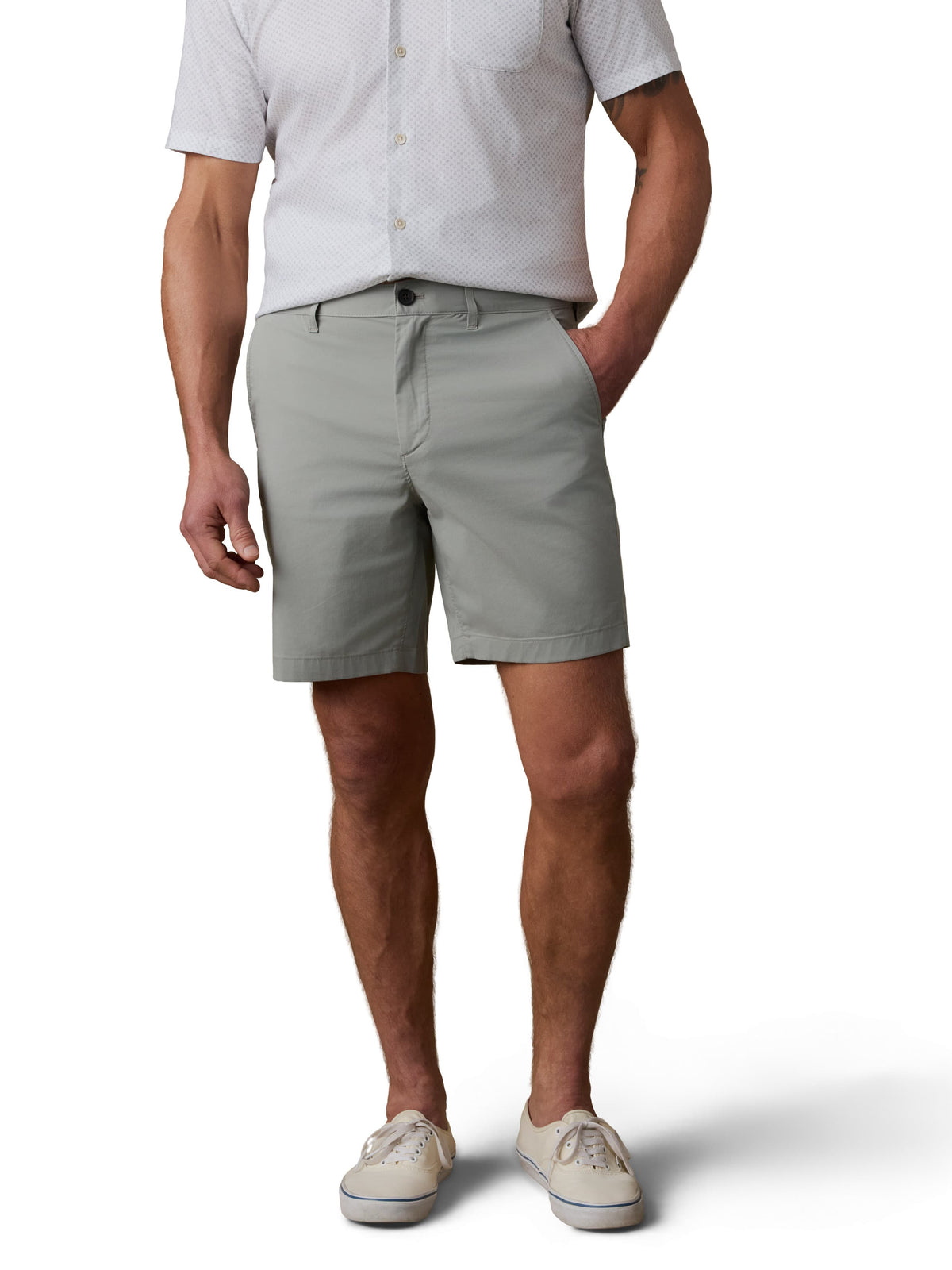 A man wearing a white button up shirt, sage green shorts, and sneakers, image 2 of 3
