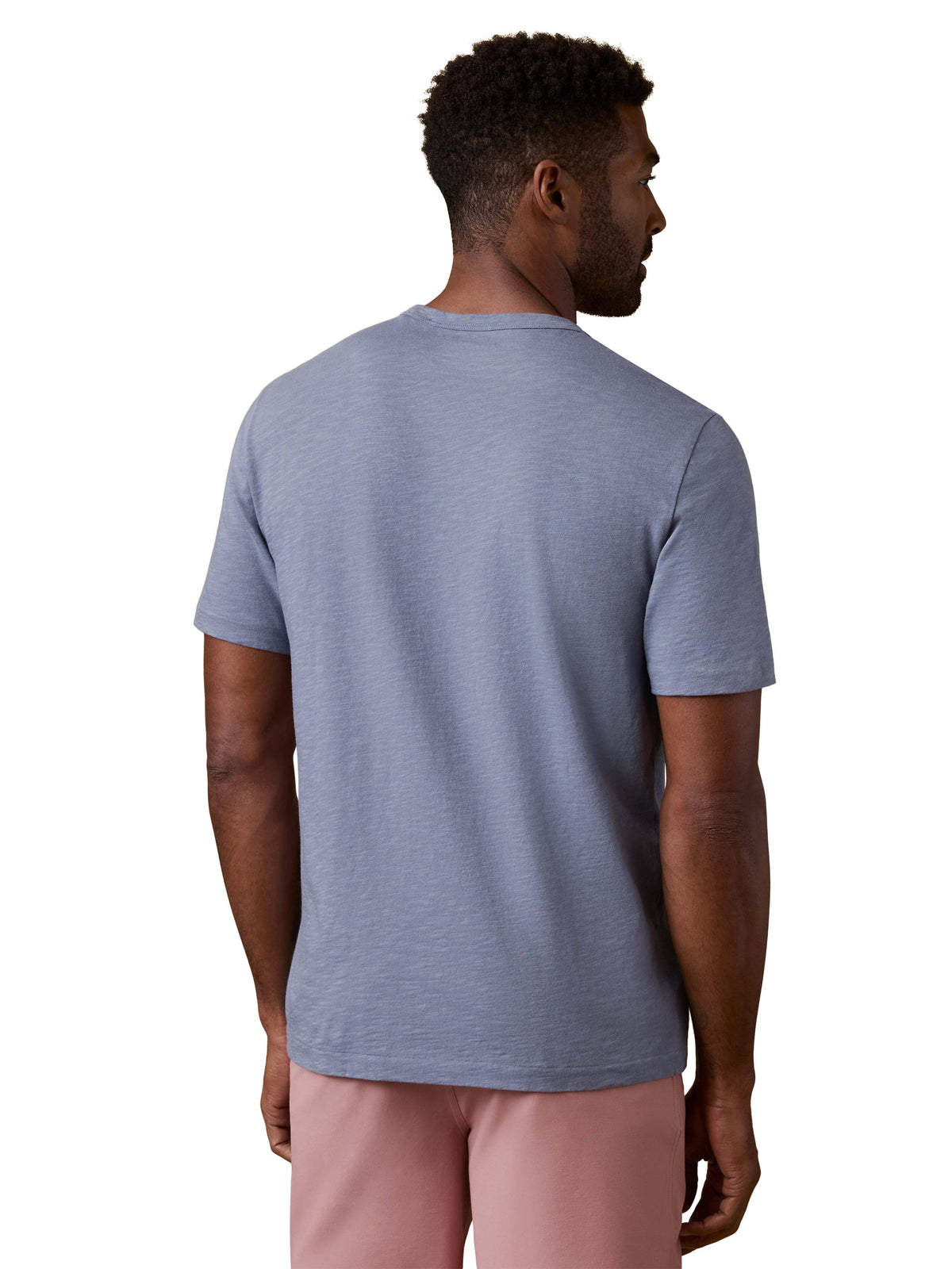 A man viewed from behind wearing a periwinkle tee and pink shorts, image 3 of 3