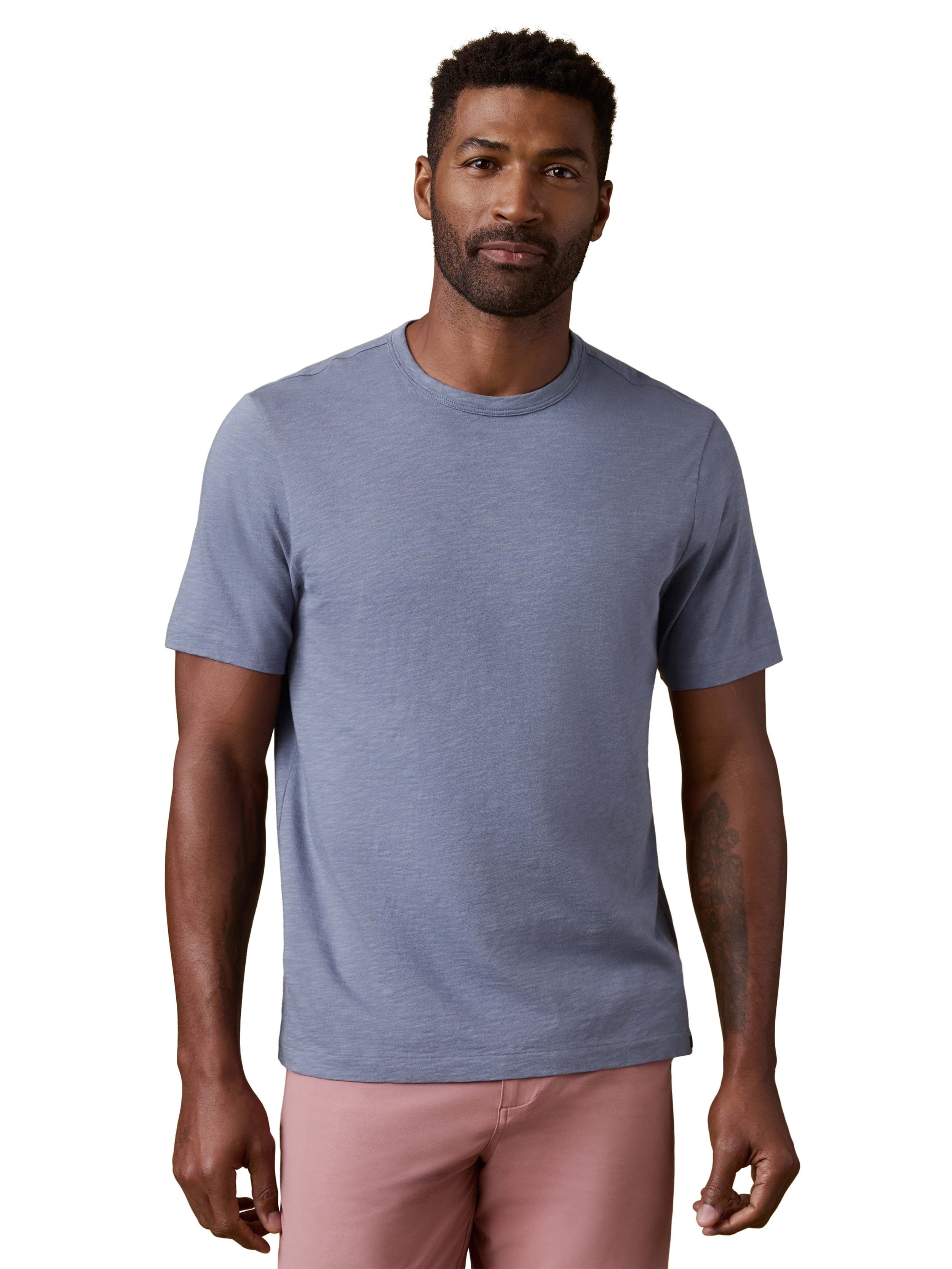 A man wearing a periwinkle tee and pink shorts