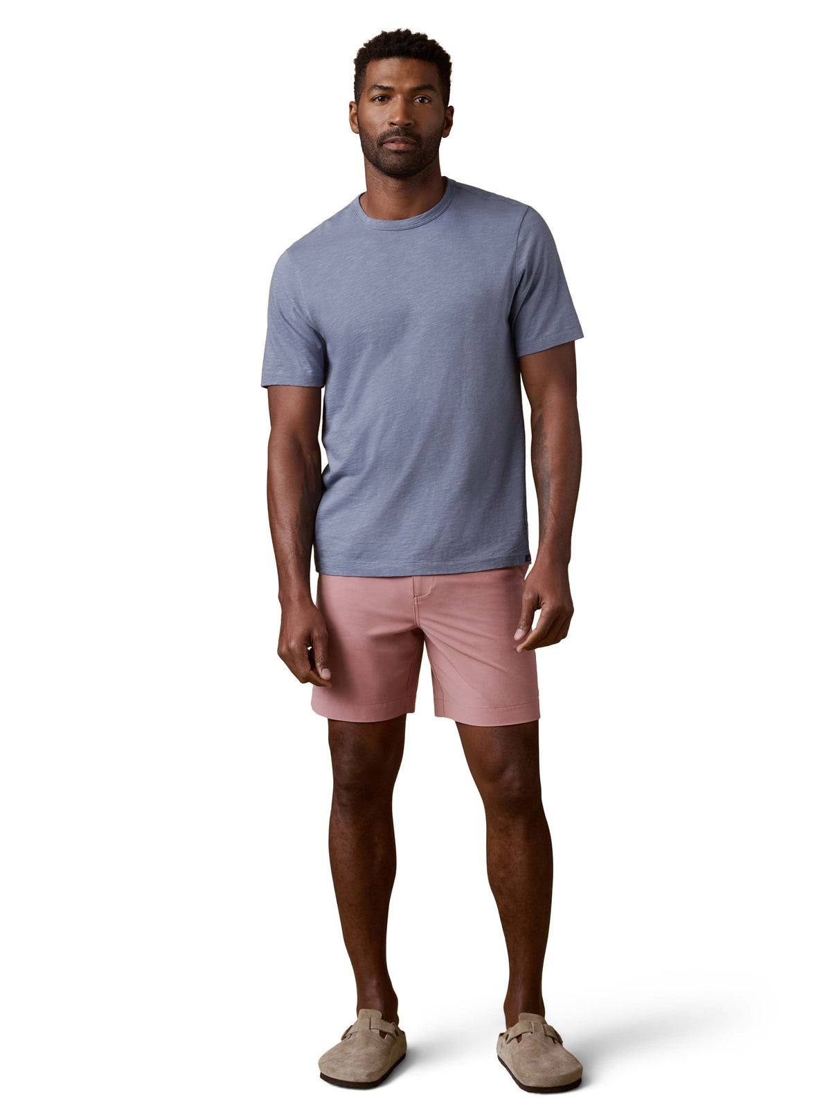A man wearing a periwinkle tee, pink shorts, and birkenstocks, image 2 of 3