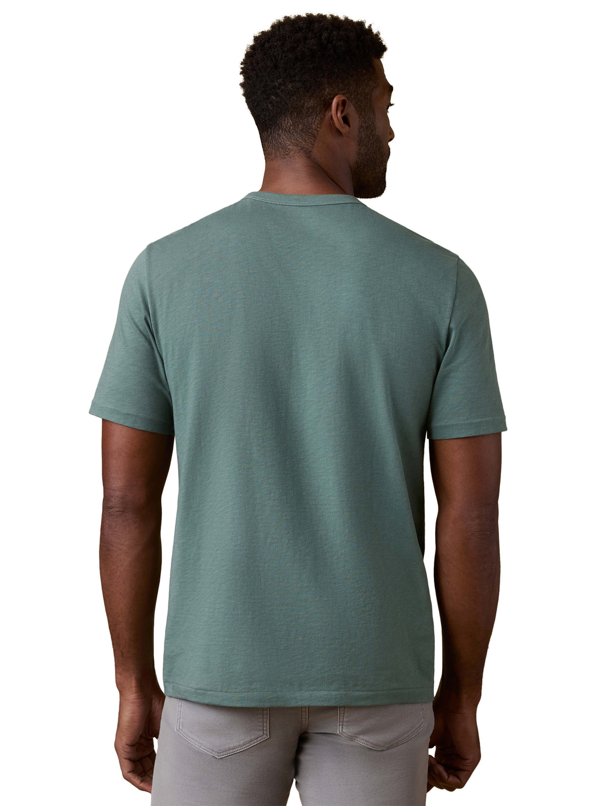 A man viewed from behind wearing a green tee and grey pants, image 3 of 3