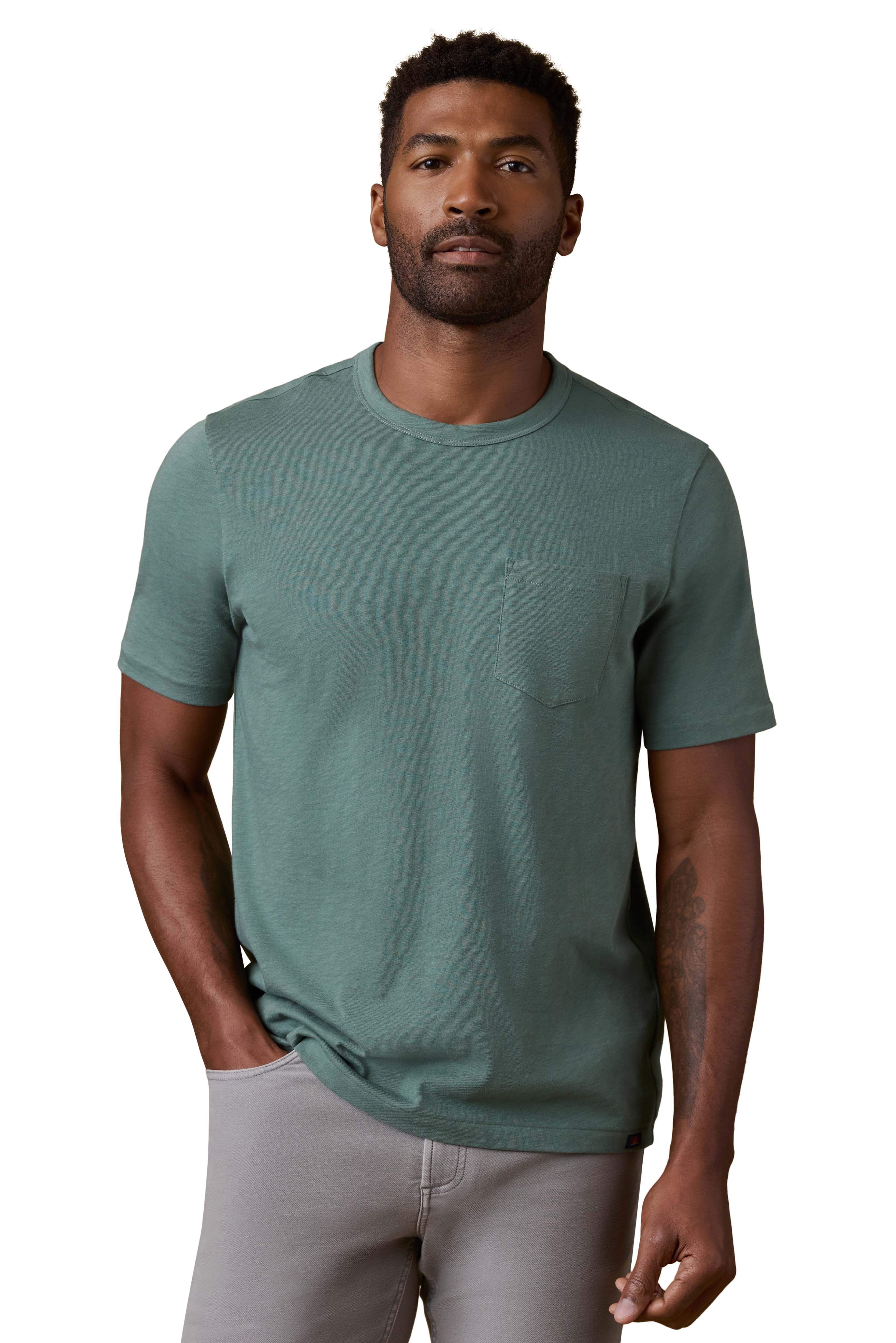A man wearing a green tee and grey pants