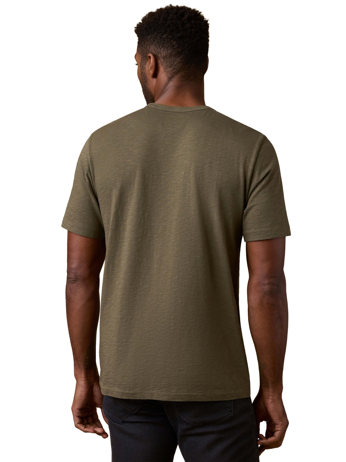 A man viewed from behind wearing a green tee and black jeans, image 3 of 3