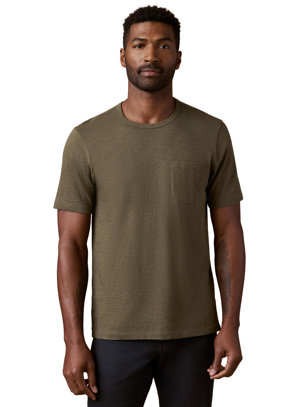 A man wearing a green tee and black jeans, image 1 of 3