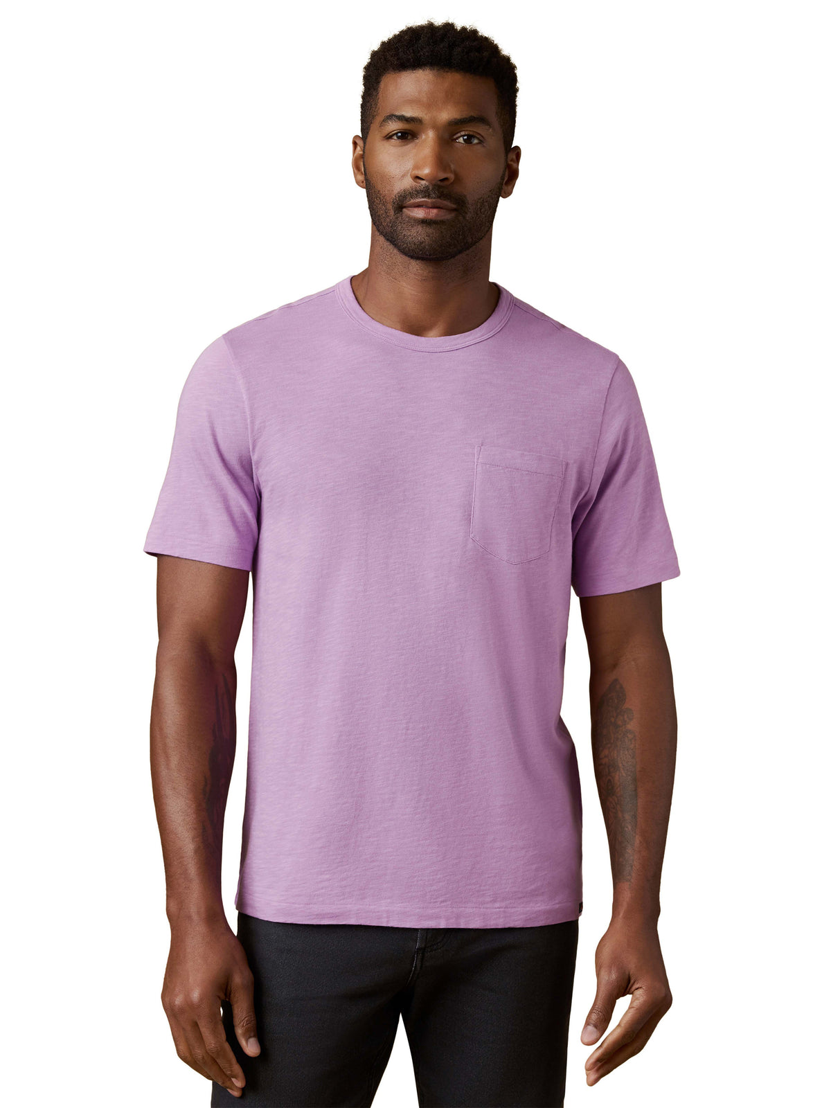 A man wearing a purple tee and black jeans, image 1 of 3