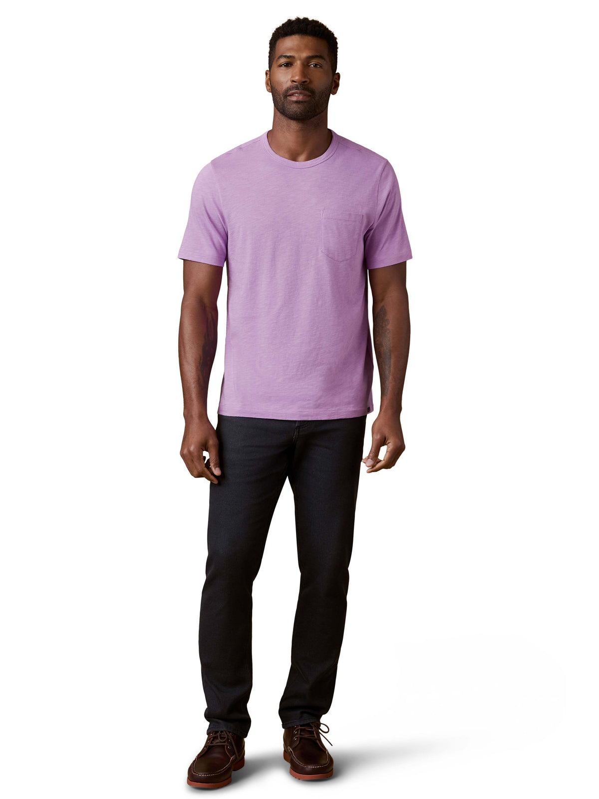 A man wearing a purple tee, black jeans, and brown shoes, image 2 of 3