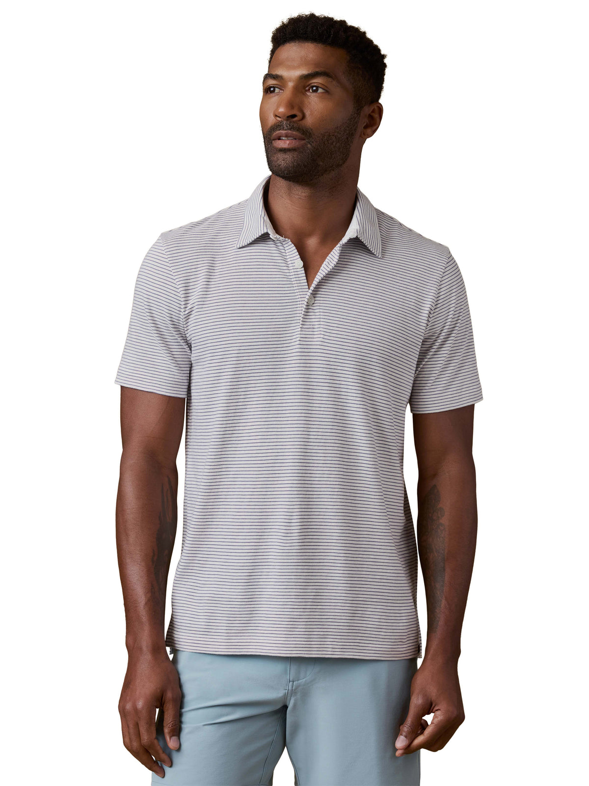 A man wearing a striped polo shirt and blue shorts, image 1 of 3