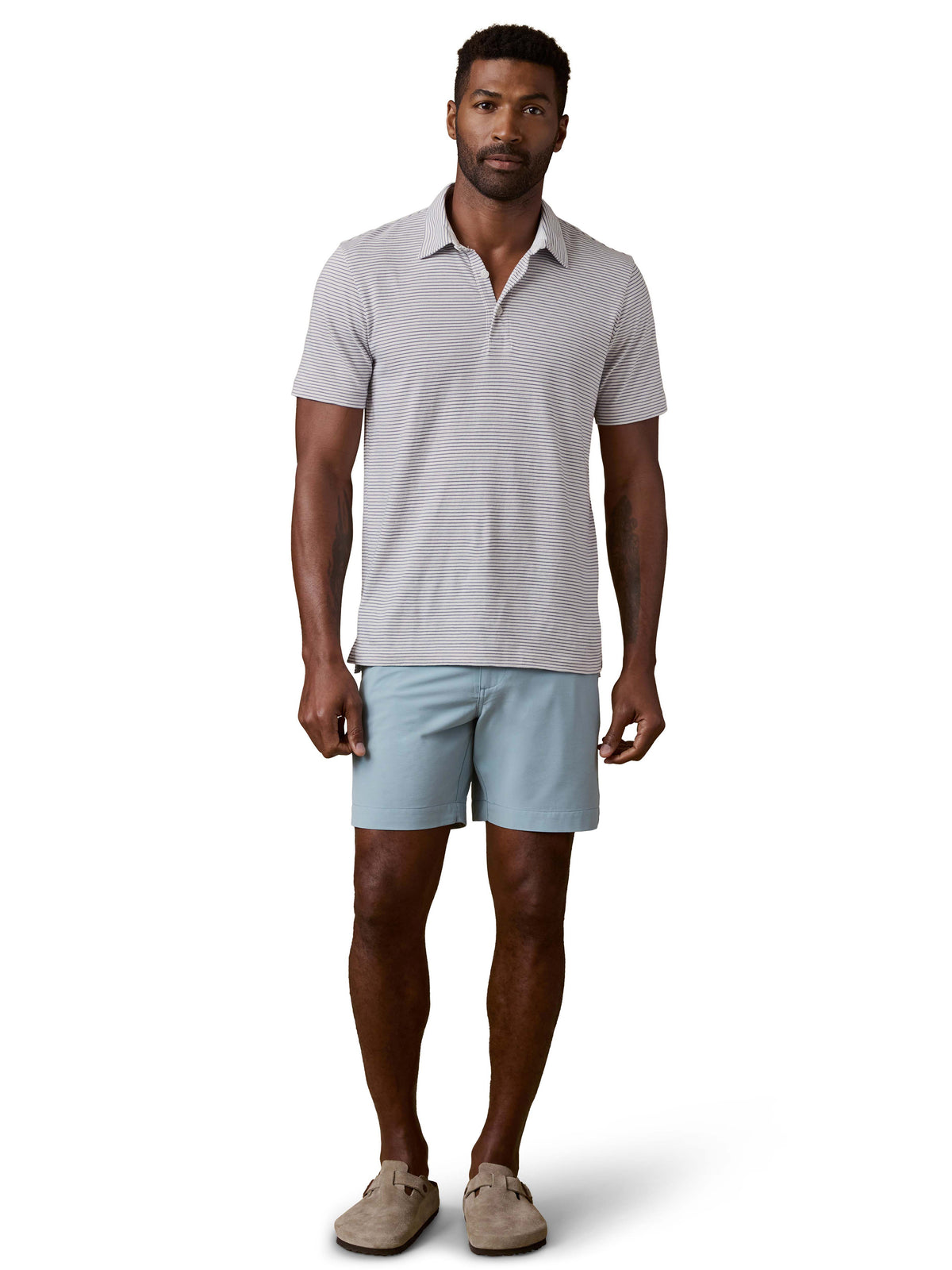 A man wearing a striped polo shirt, blue shorts, and birkenstocks, image 2 of 3