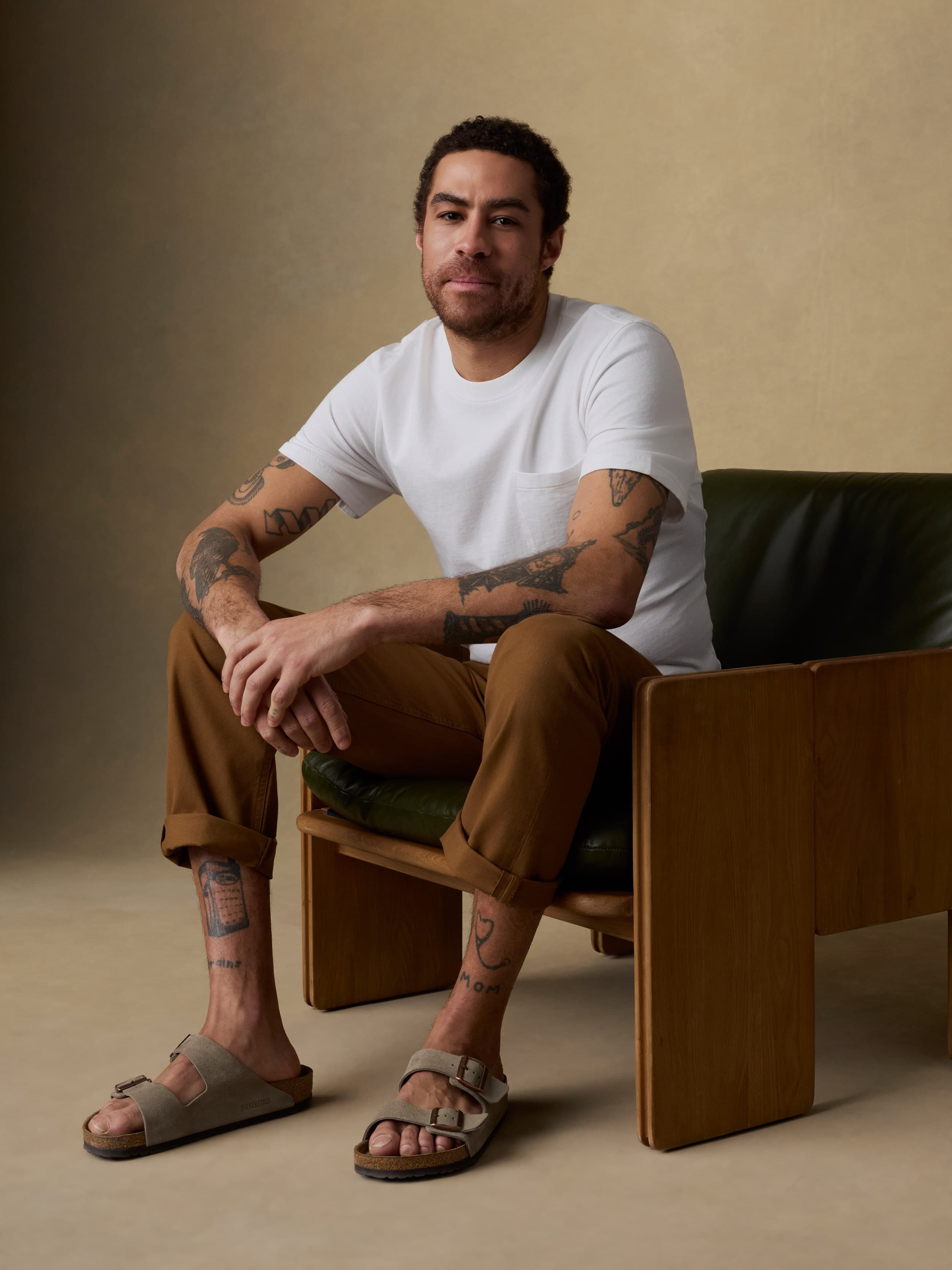 Man sitting on a brown leather chair against a beige background
