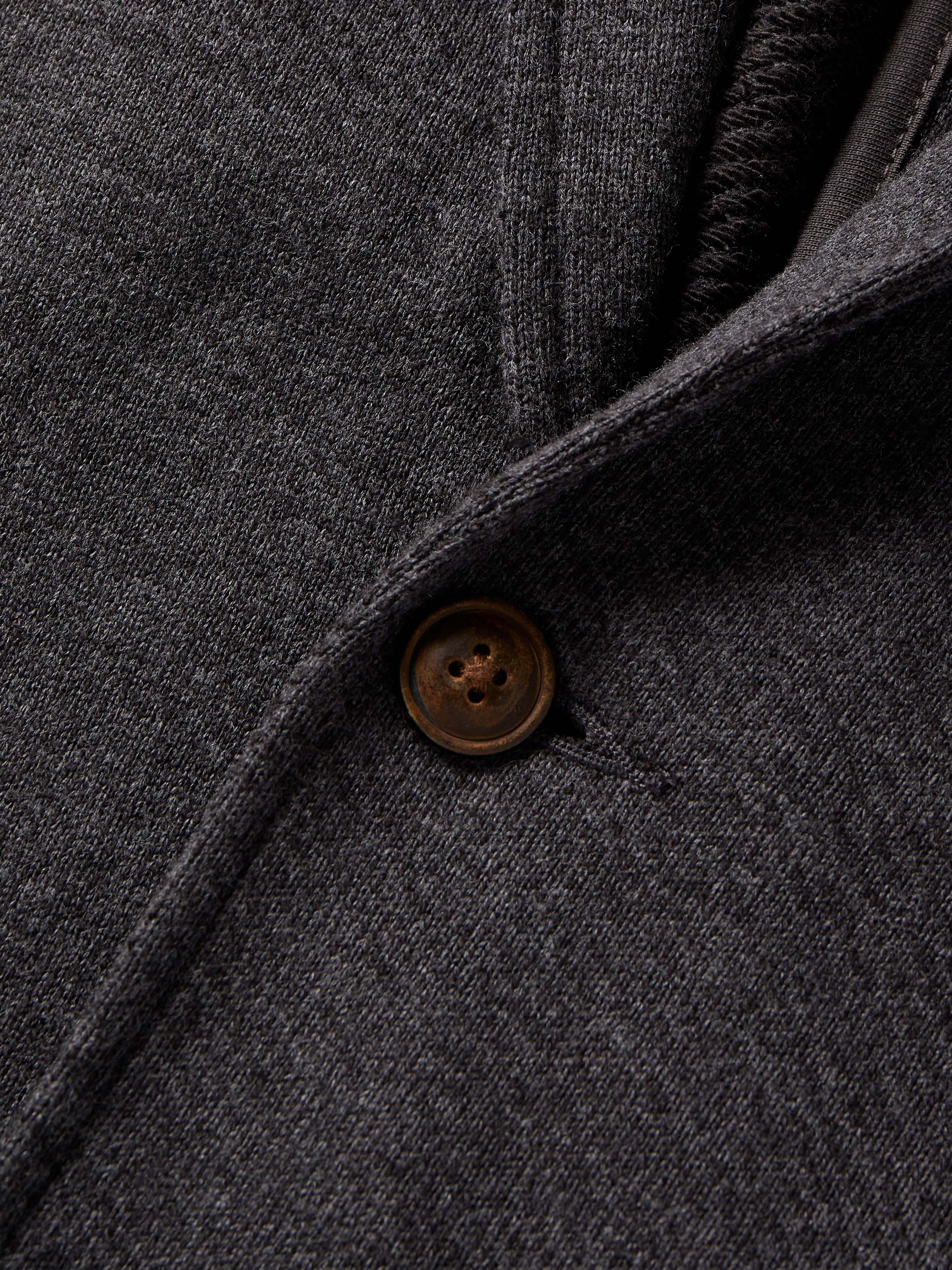 Close-up of a dark gray fabric with a button, likely from a coat or jacket.