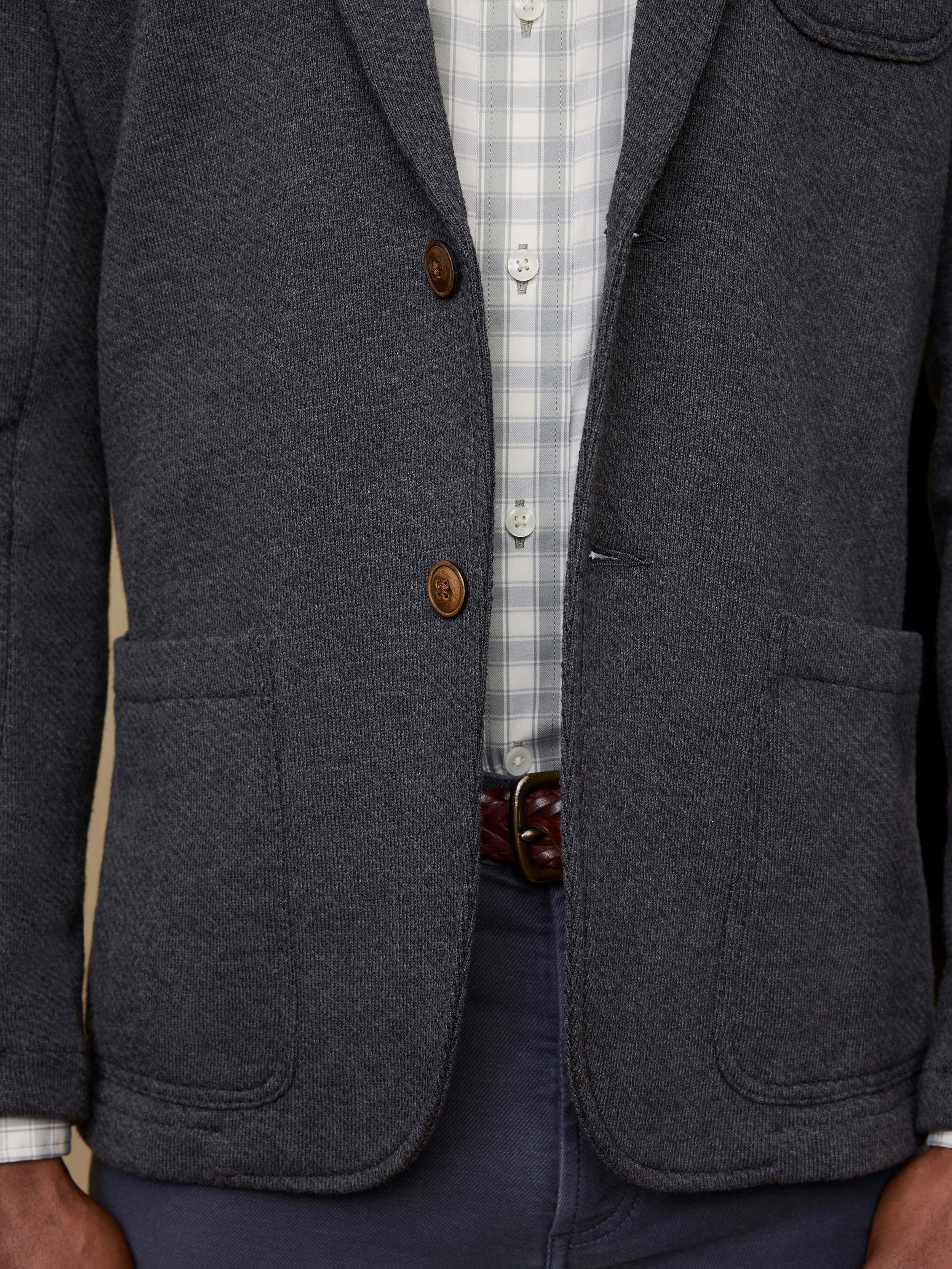 Gray blazer with brown buttons worn over a checkered shirt.