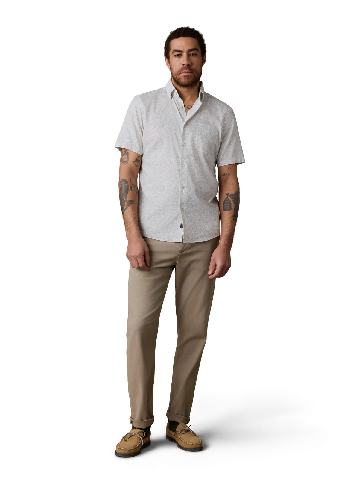 A man wearing a white button up shirt, beige pants, and boat shoes, image 2 of 3