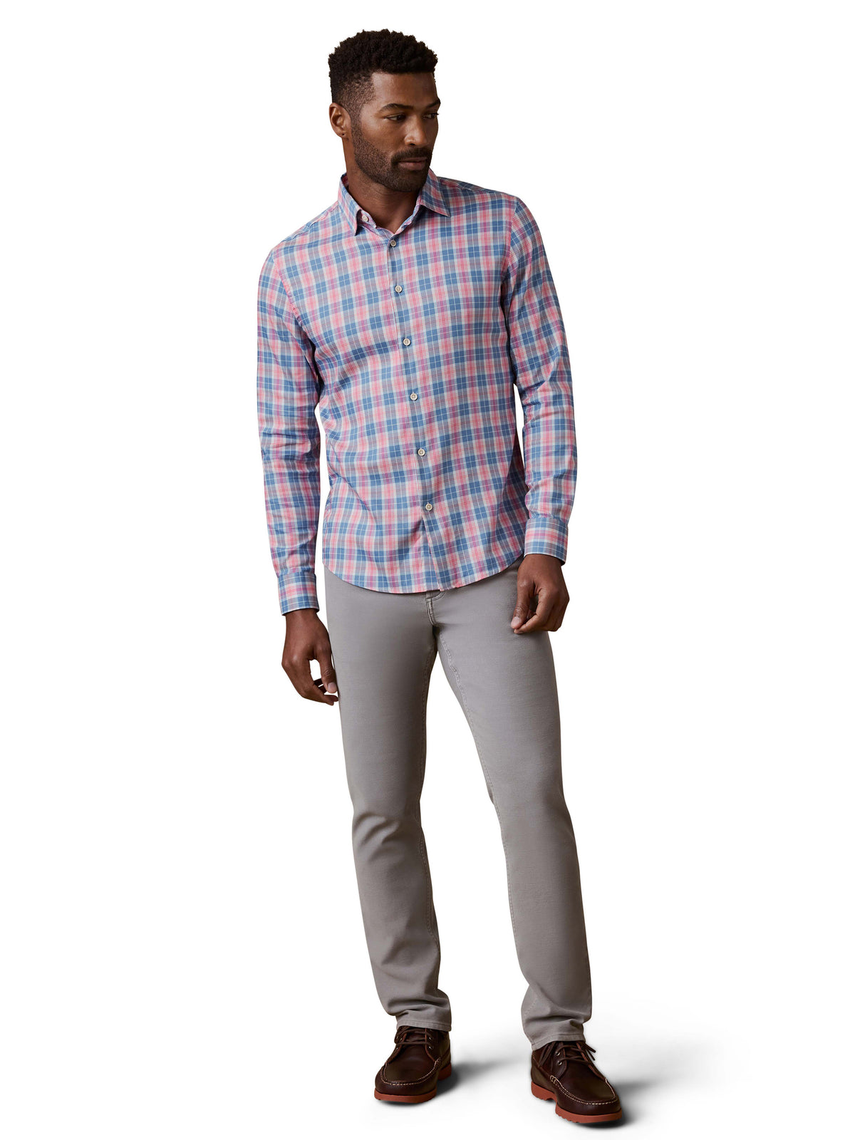 A man wearing a red and blue plaid shirt, grey pants, and brown shoes, image 2 of 3